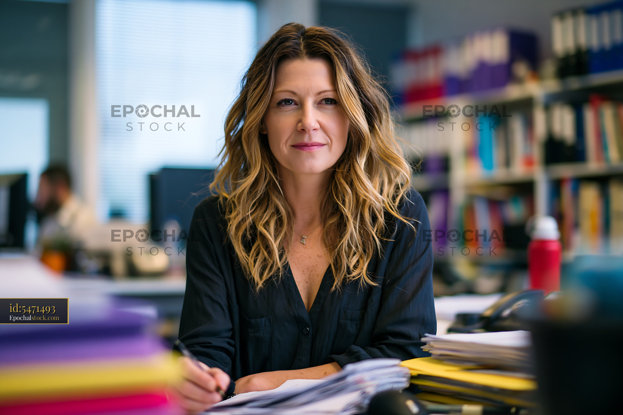 Watermarked full-resolution preview of Woman working in an office with papers and documents on desk