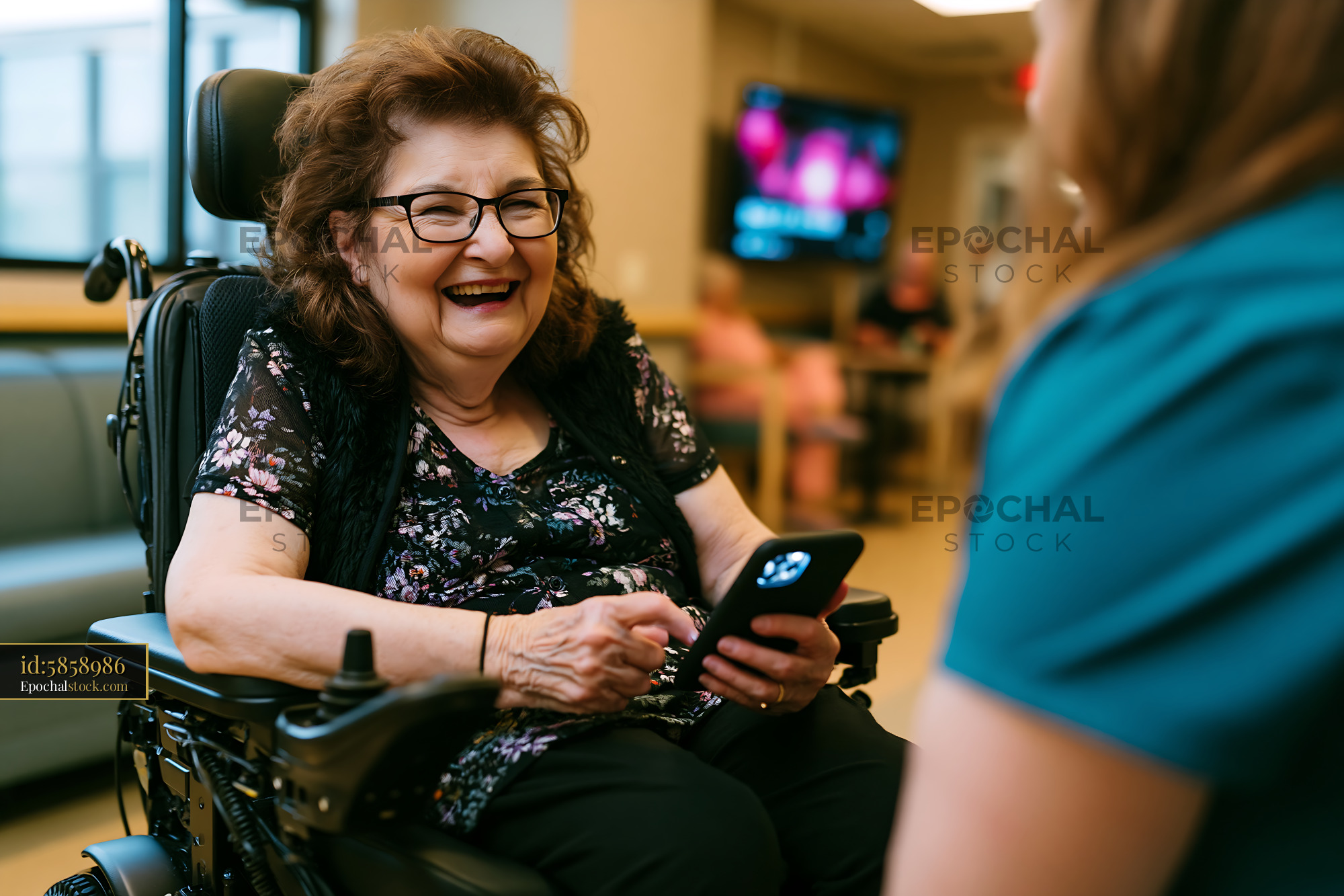 Watermarked full-resolution preview of Happy woman in a wheelchair using a smartphone indoors