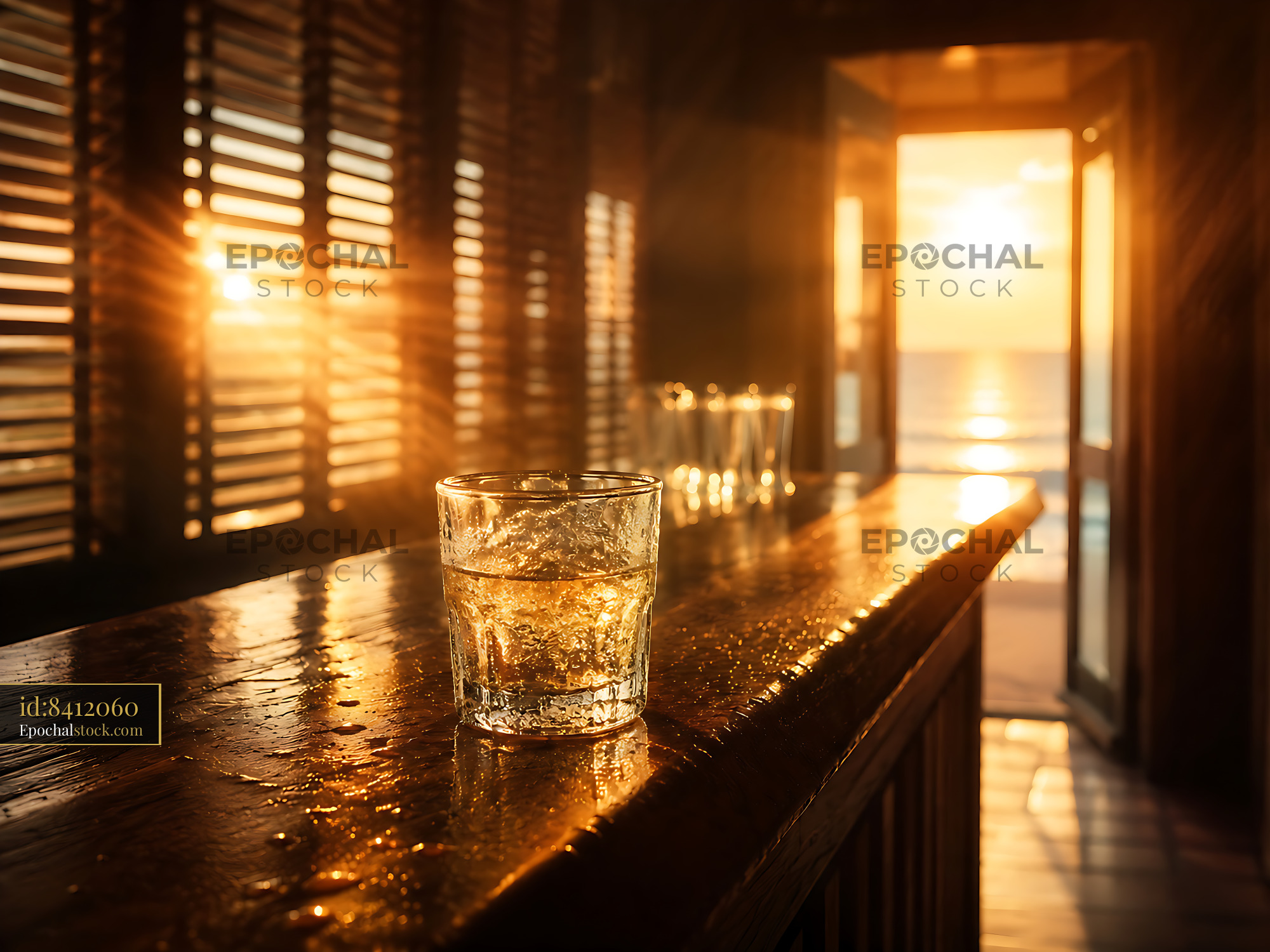 Glass of Water on Wooden Counter With Sunset View Over Ocean - stock photo