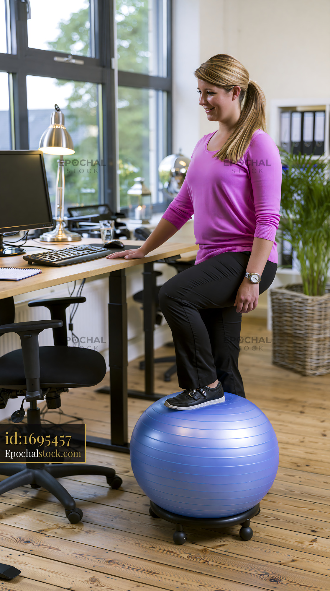 Watermarked full-resolution preview of Woman balancing on fitness ball in office environment
