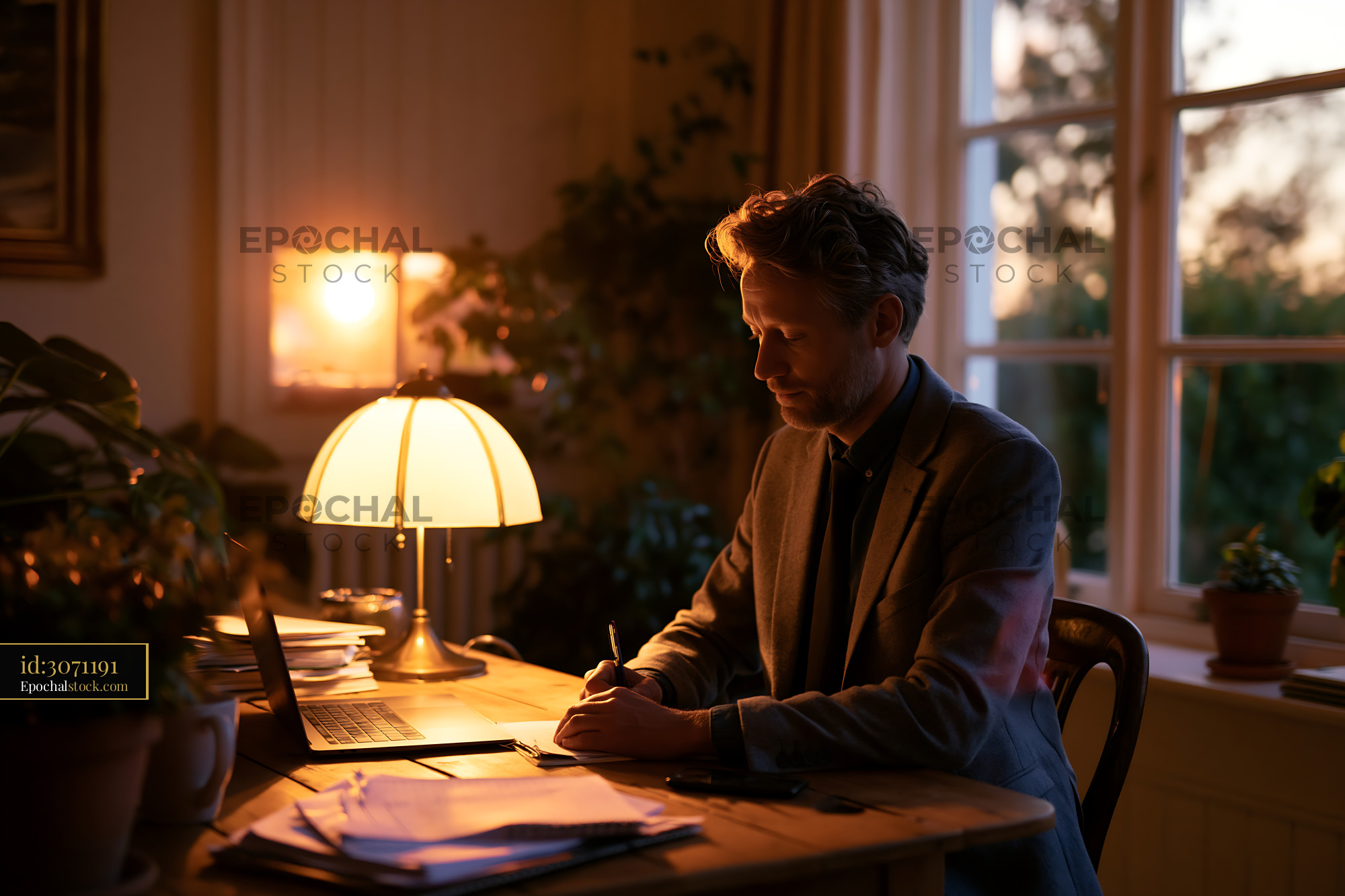 Watermarked full-resolution preview of Working at a desk with a laptop and lamp in warm evening light