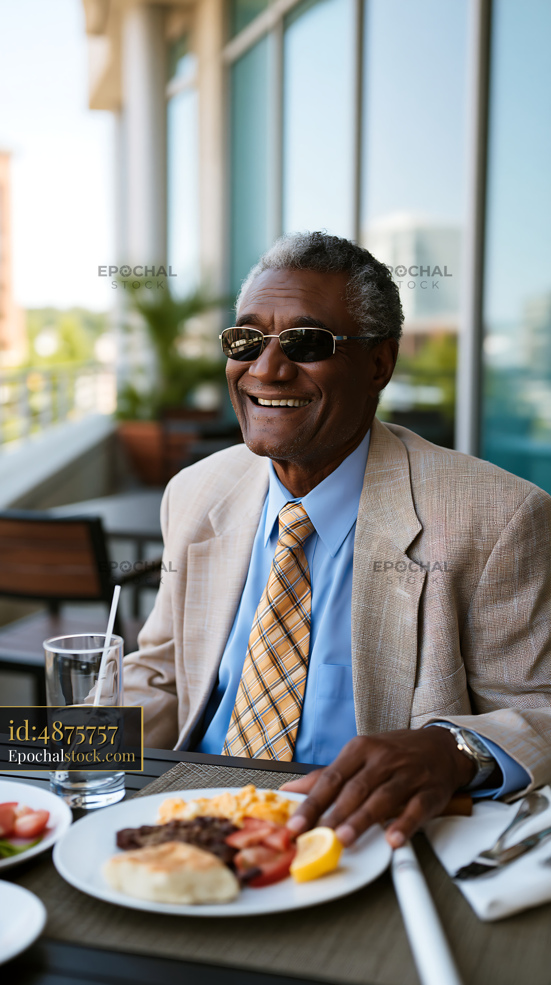 Watermarked full-resolution preview of Man enjoys breakfast on a restaurant patio with a smile