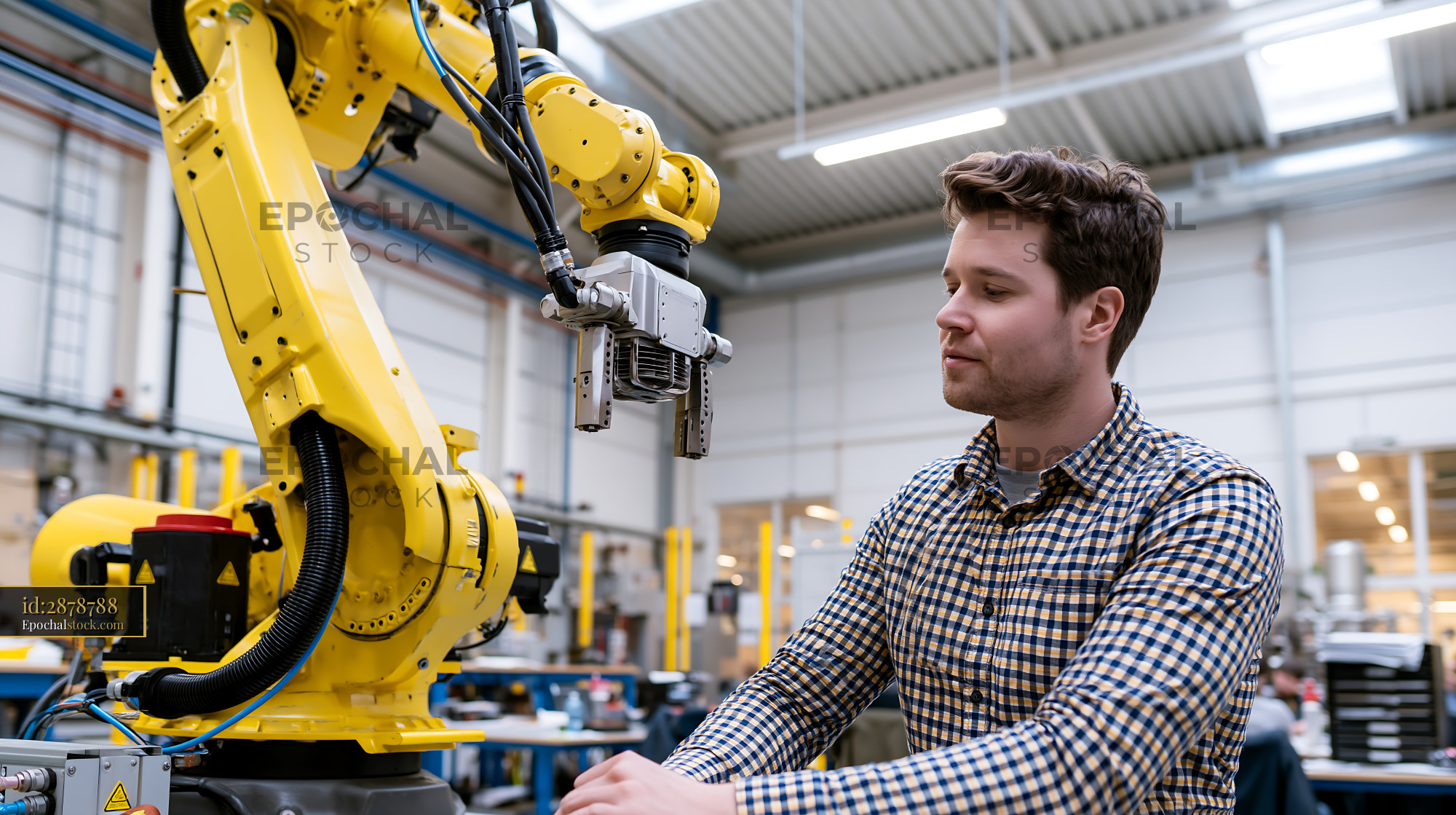 Watermarked full-resolution preview of Worker operates robotic arm in industrial workshop