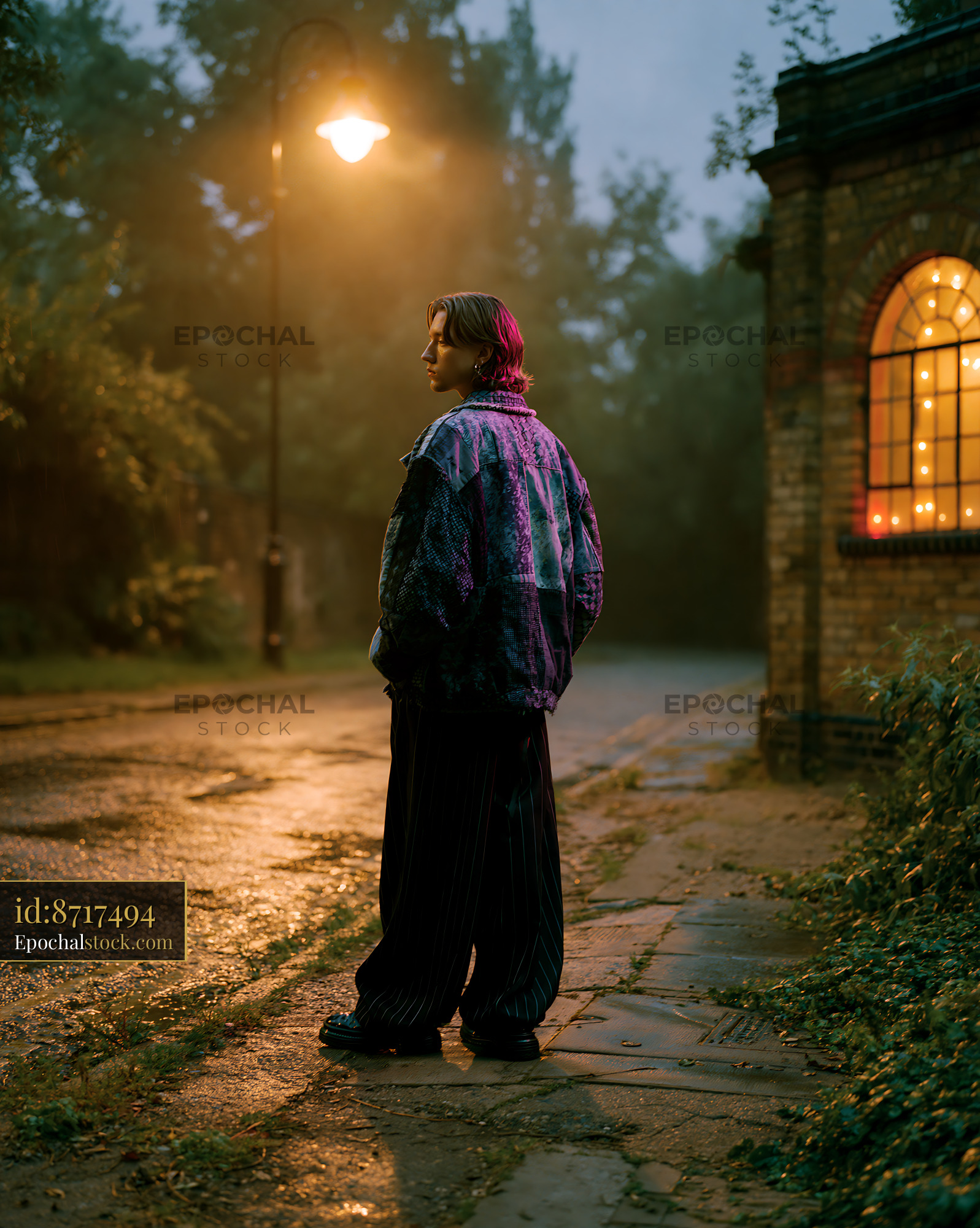 Watermarked full-resolution preview of Person standing on a wet street near a building at night