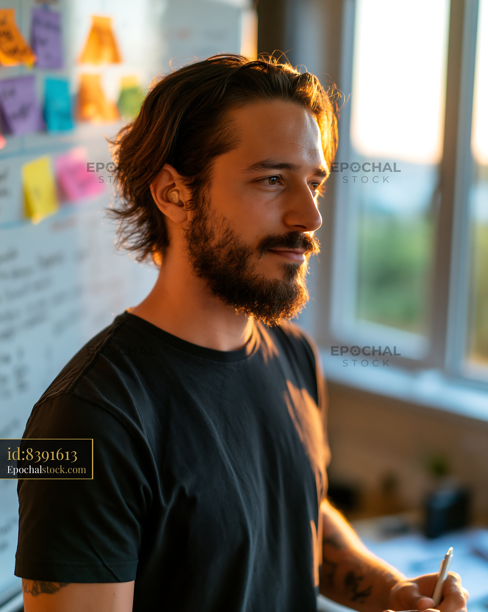 Watermarked full-resolution preview of Man standing in a room with notes on a wall during sunset