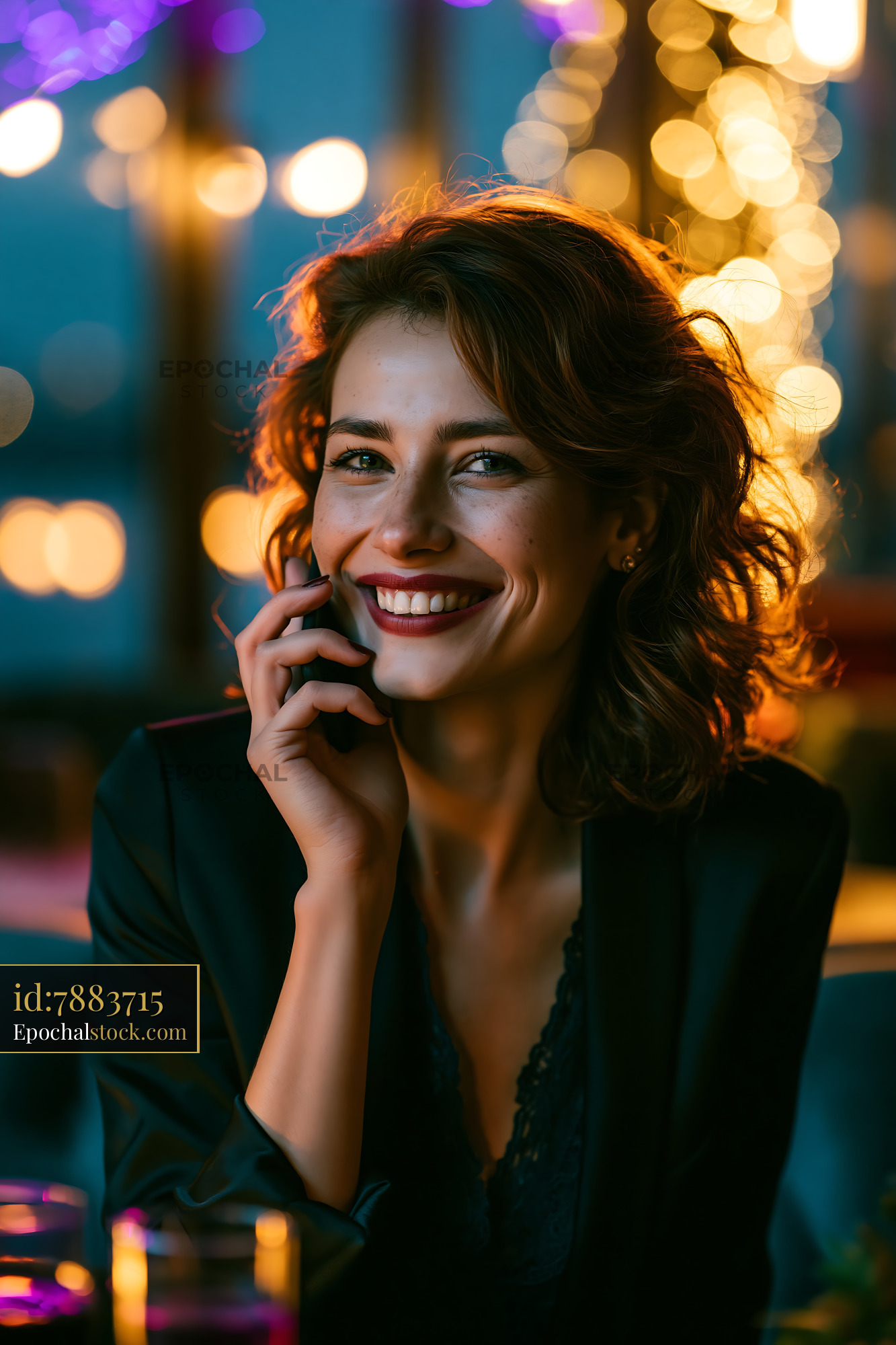Woman Smiling While Talking on the Phone in a Dimly Lit Space - stock photo