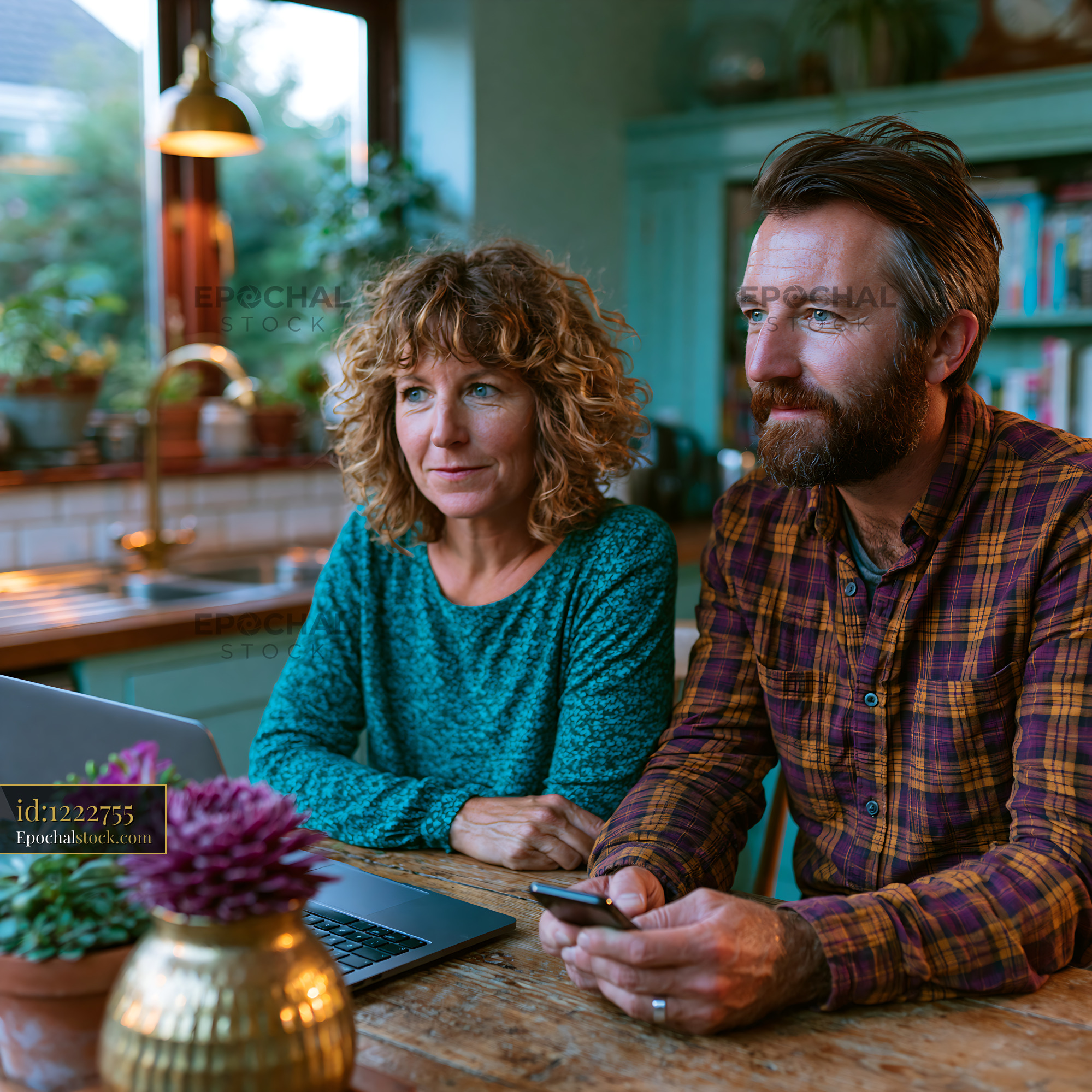 Watermarked full-resolution preview of Couple using a laptop and smartphone at a kitchen table