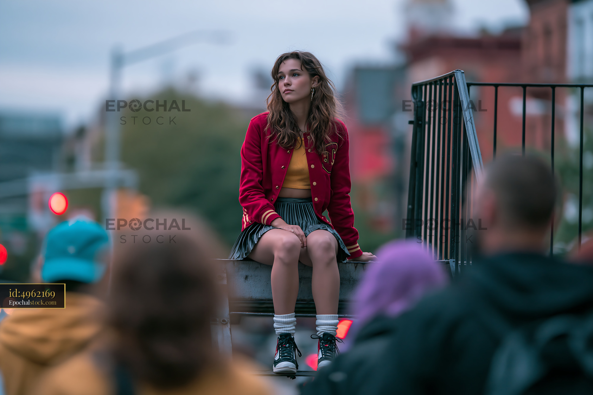 Watermarked full-resolution preview of Girl sitting on railing in urban setting with blurred crowd below