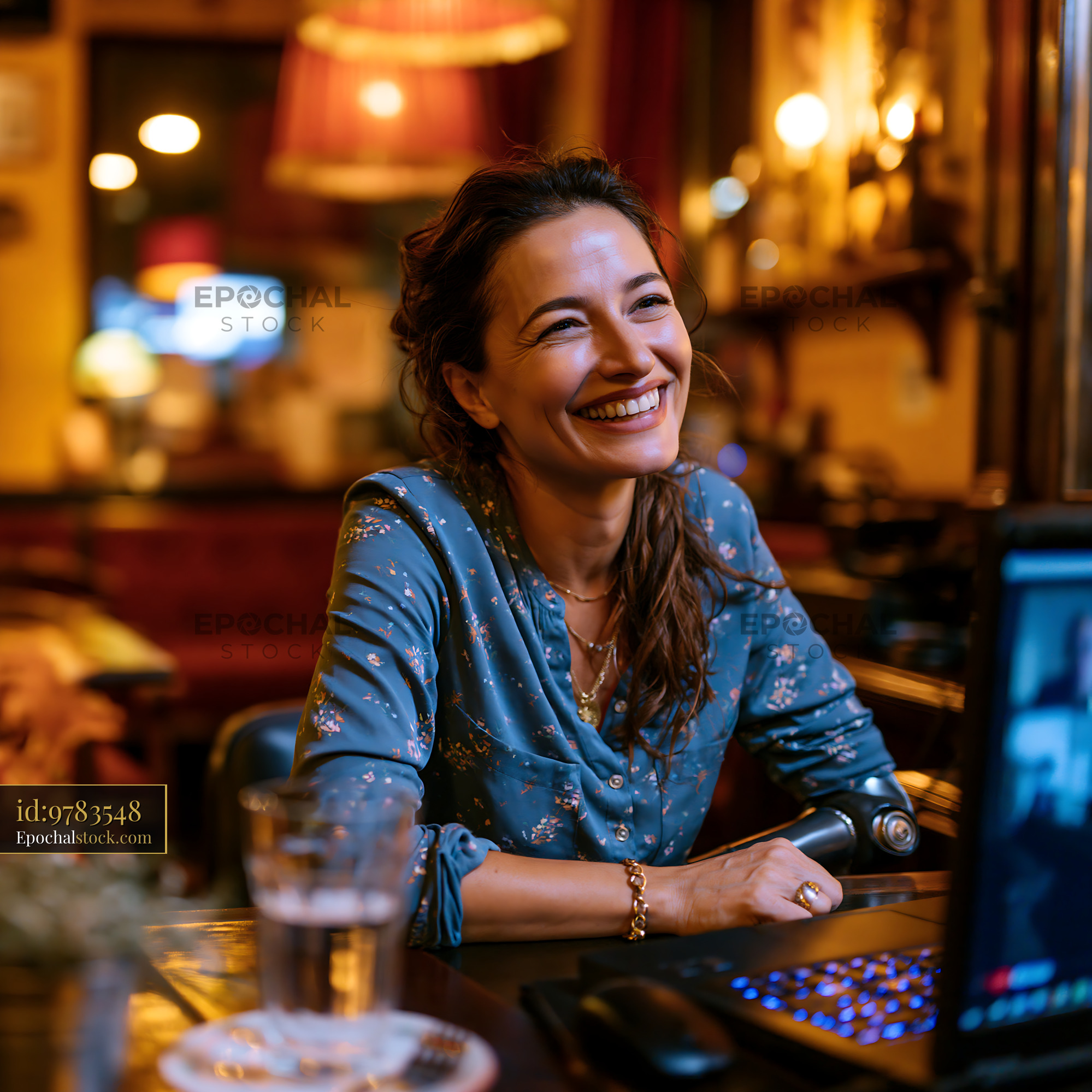 Watermarked full-resolution preview of Woman in blue blouse smiling at a table in a bar