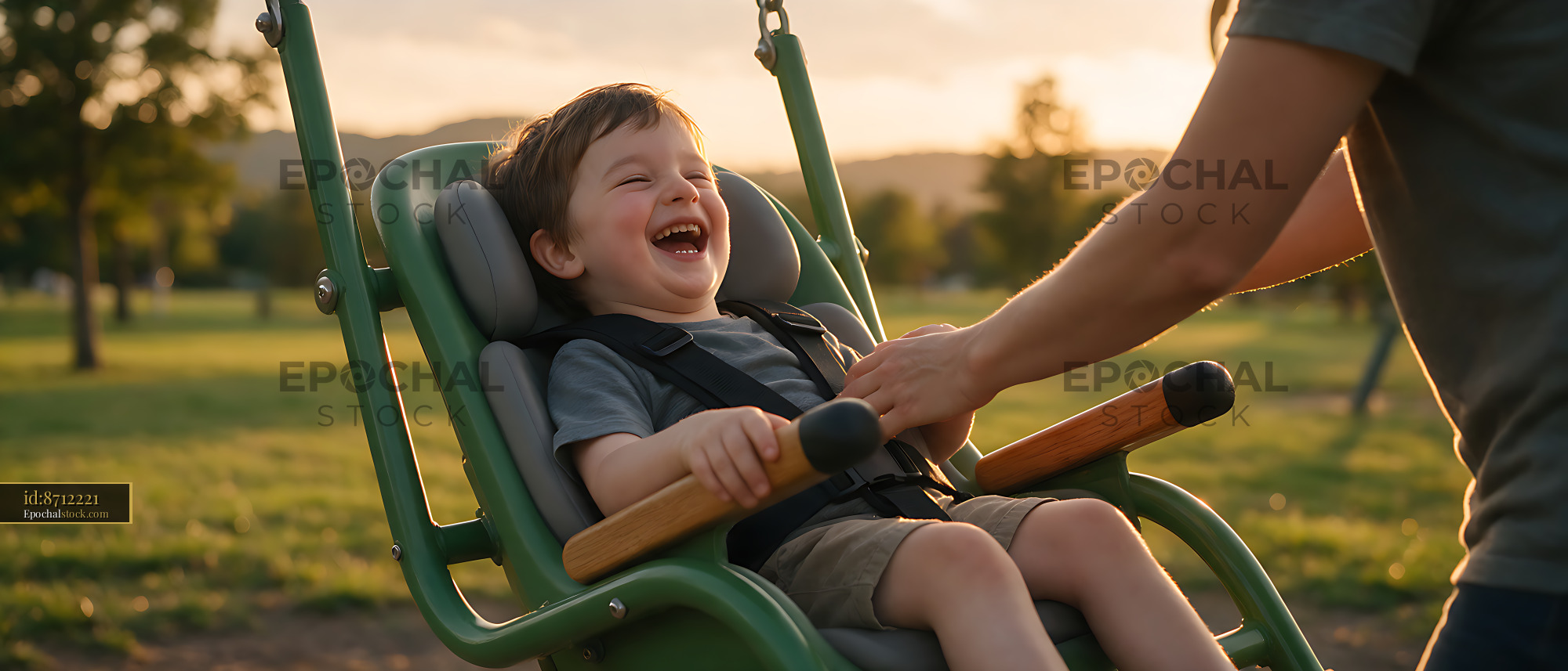 Watermarked full-resolution preview of Laughing child enjoying an inclusive playground swing