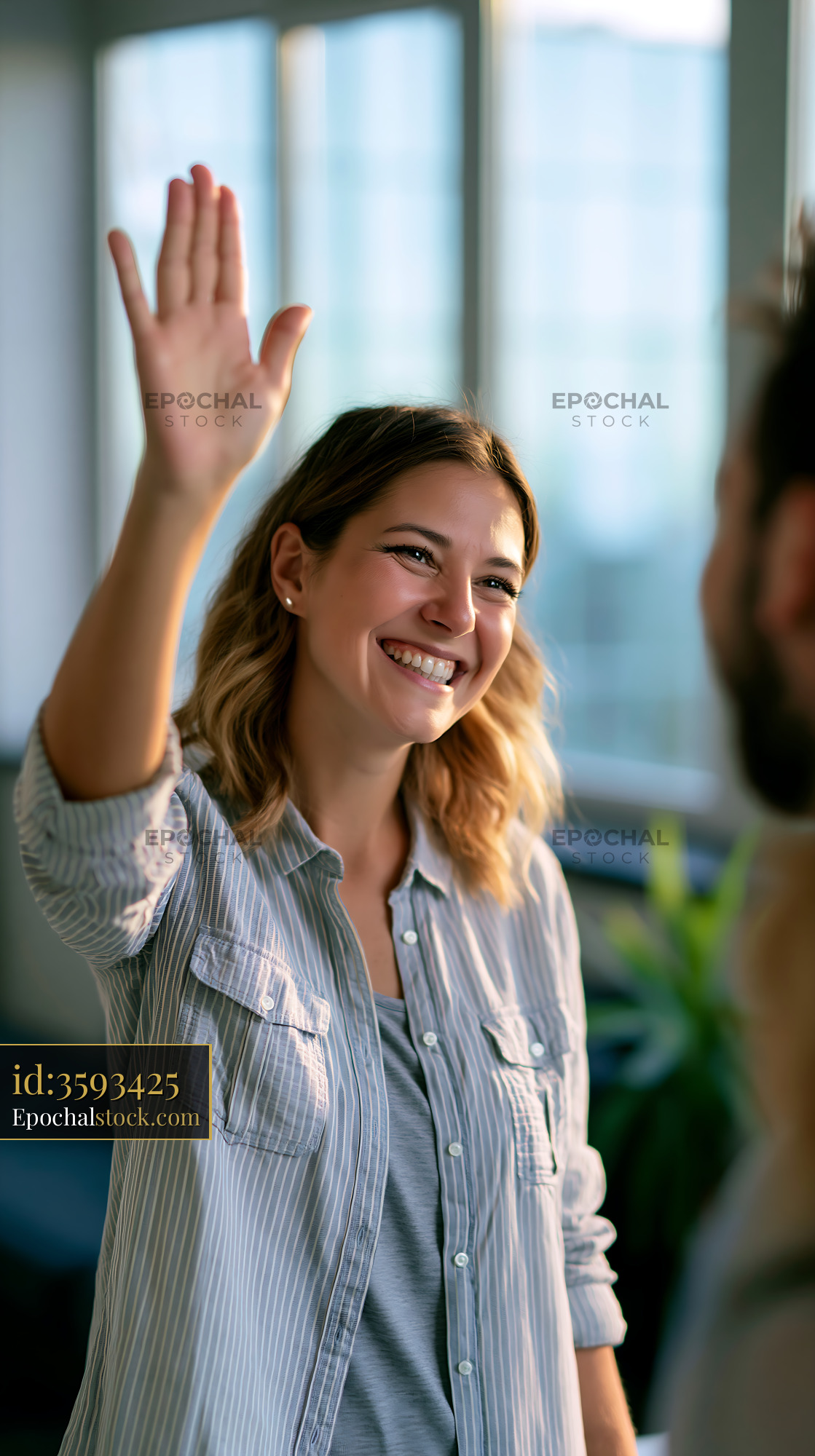 Watermarked full-resolution preview of Person smiling and waving in an office setting during daylight
