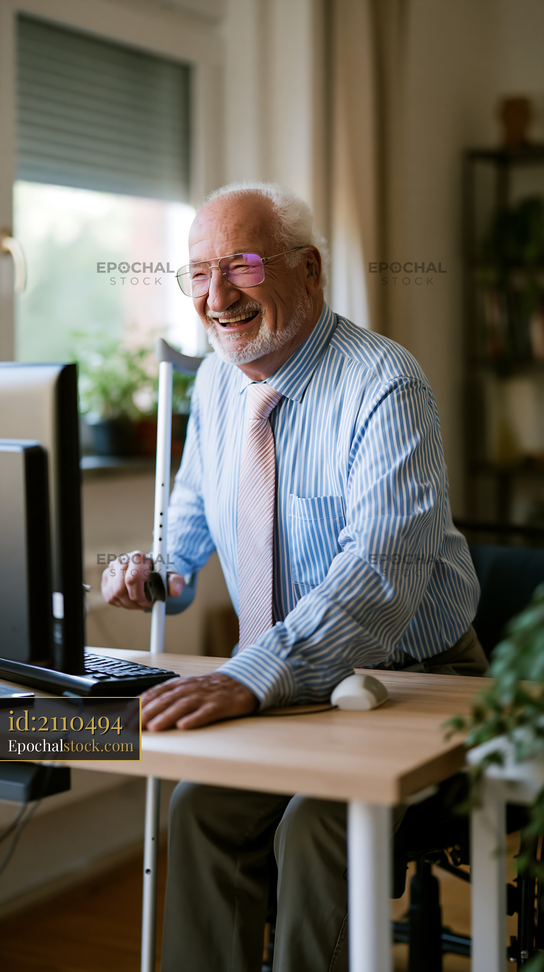 Watermarked full-resolution preview of Elderly man using a computer at home with a cane nearby