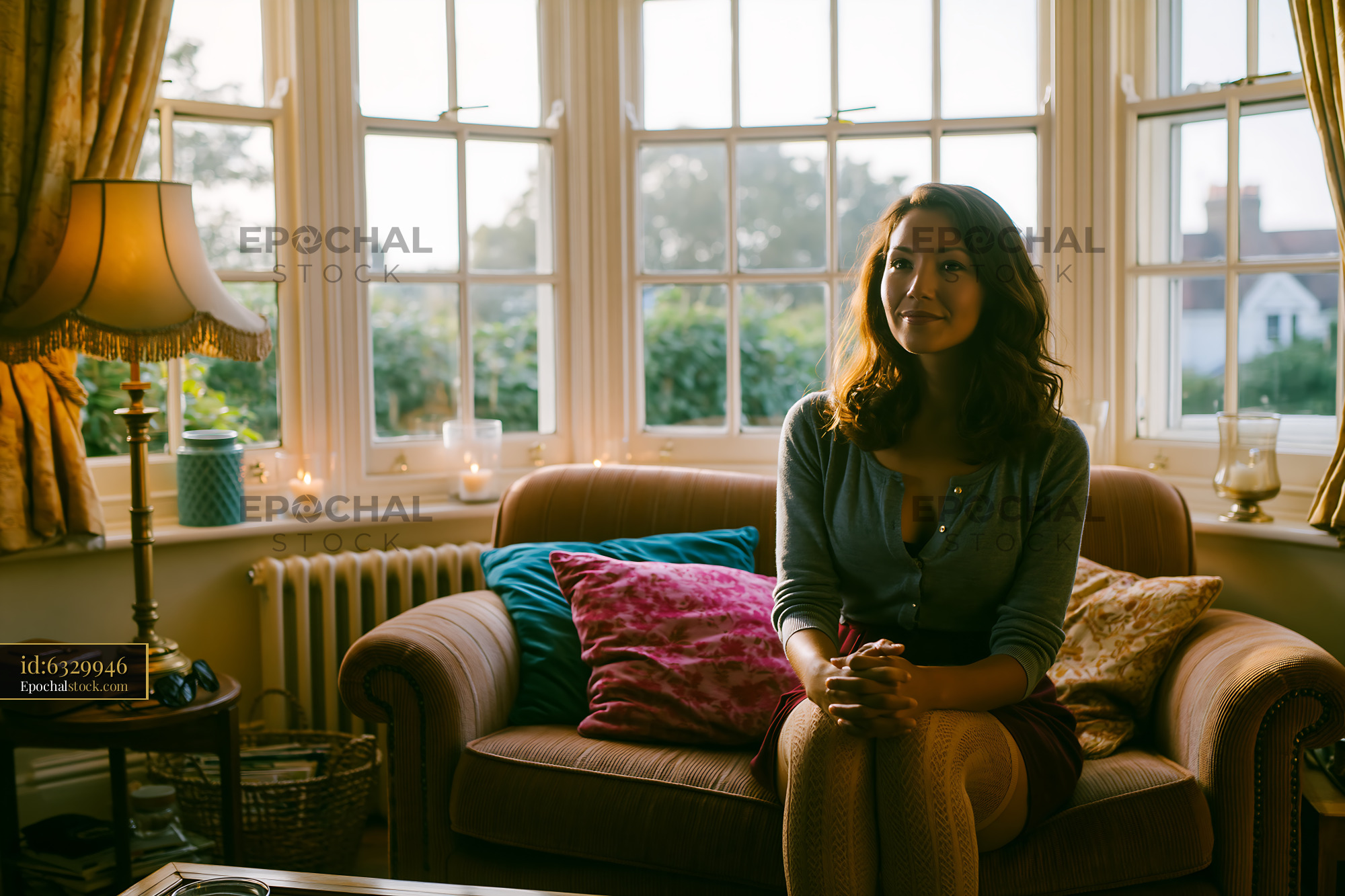 Watermarked full-resolution preview of Woman sitting on a sofa in a sunlit living room
