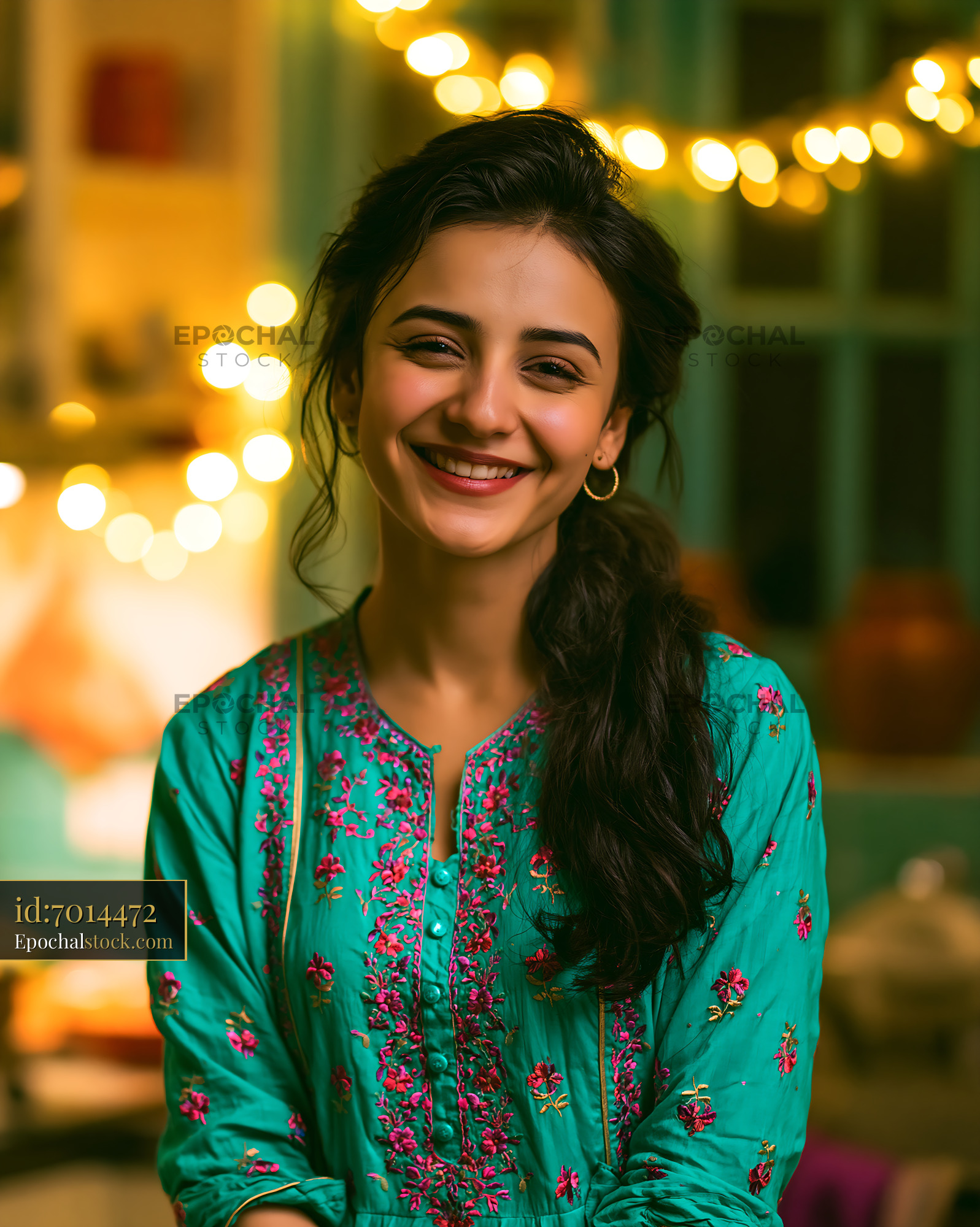 Watermarked full-resolution preview of Woman smiling in traditional attire with fairy lights in background