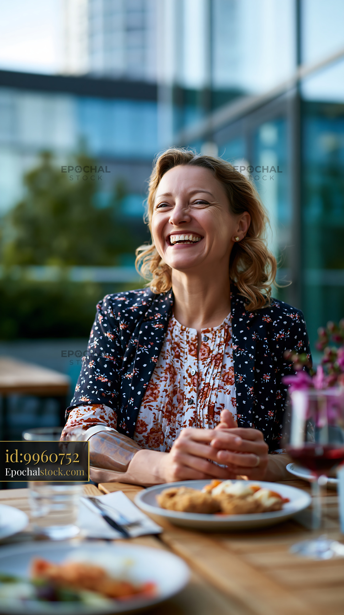 Watermarked full-resolution preview of Woman smiling while sitting at a table outdoors in a cafe