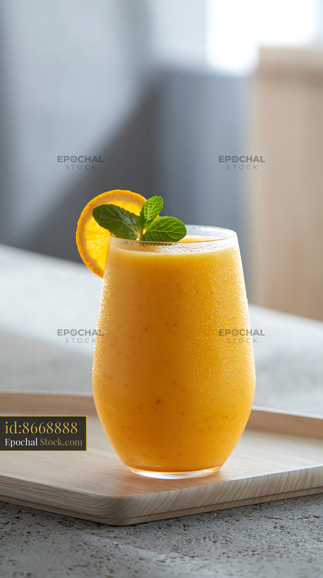 Fresh mikan orange smoothie with mint garnish on a wooden tray - stock photo