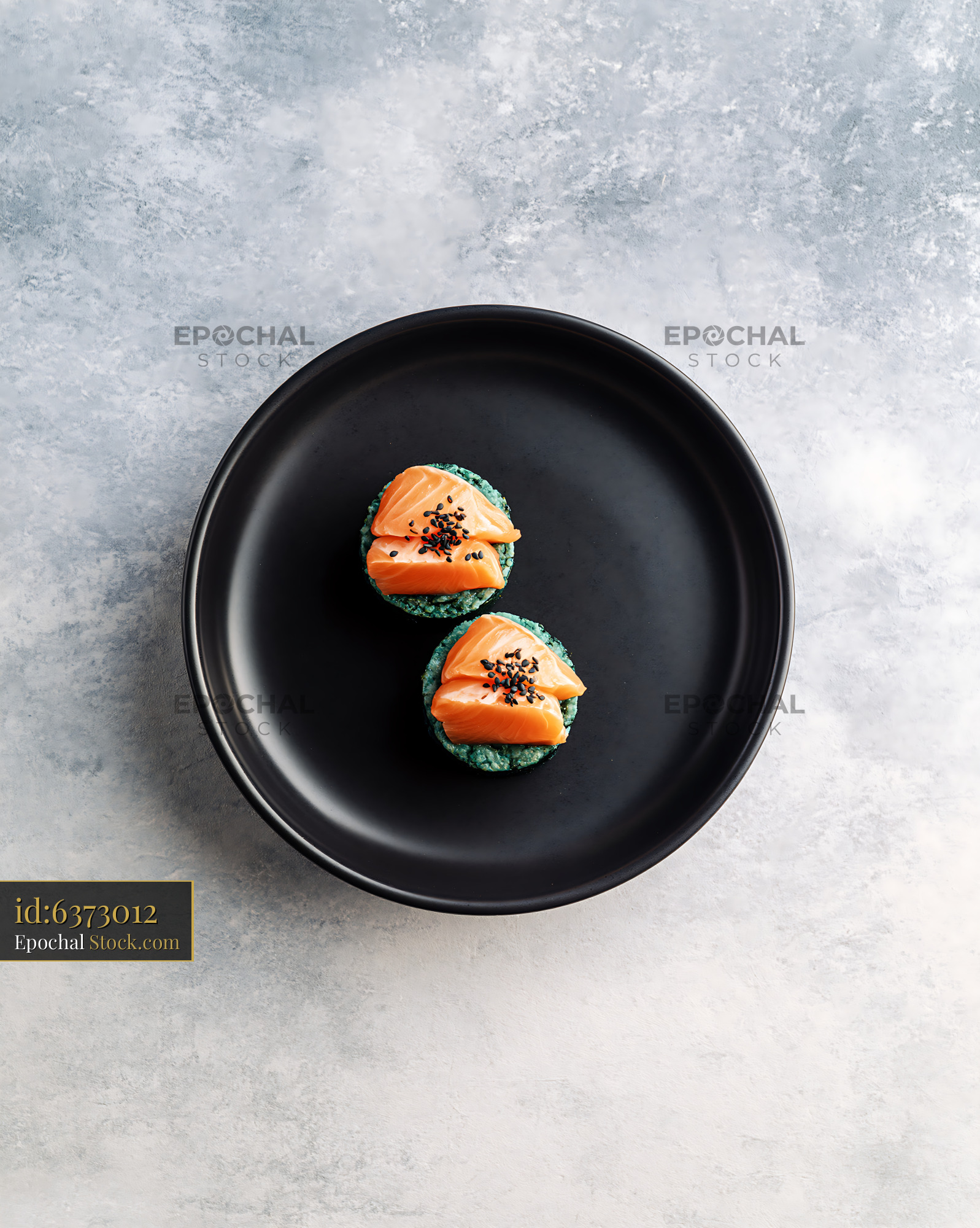 Salmon sushi appetizers with green spirulina rice on a black plate - stock photo