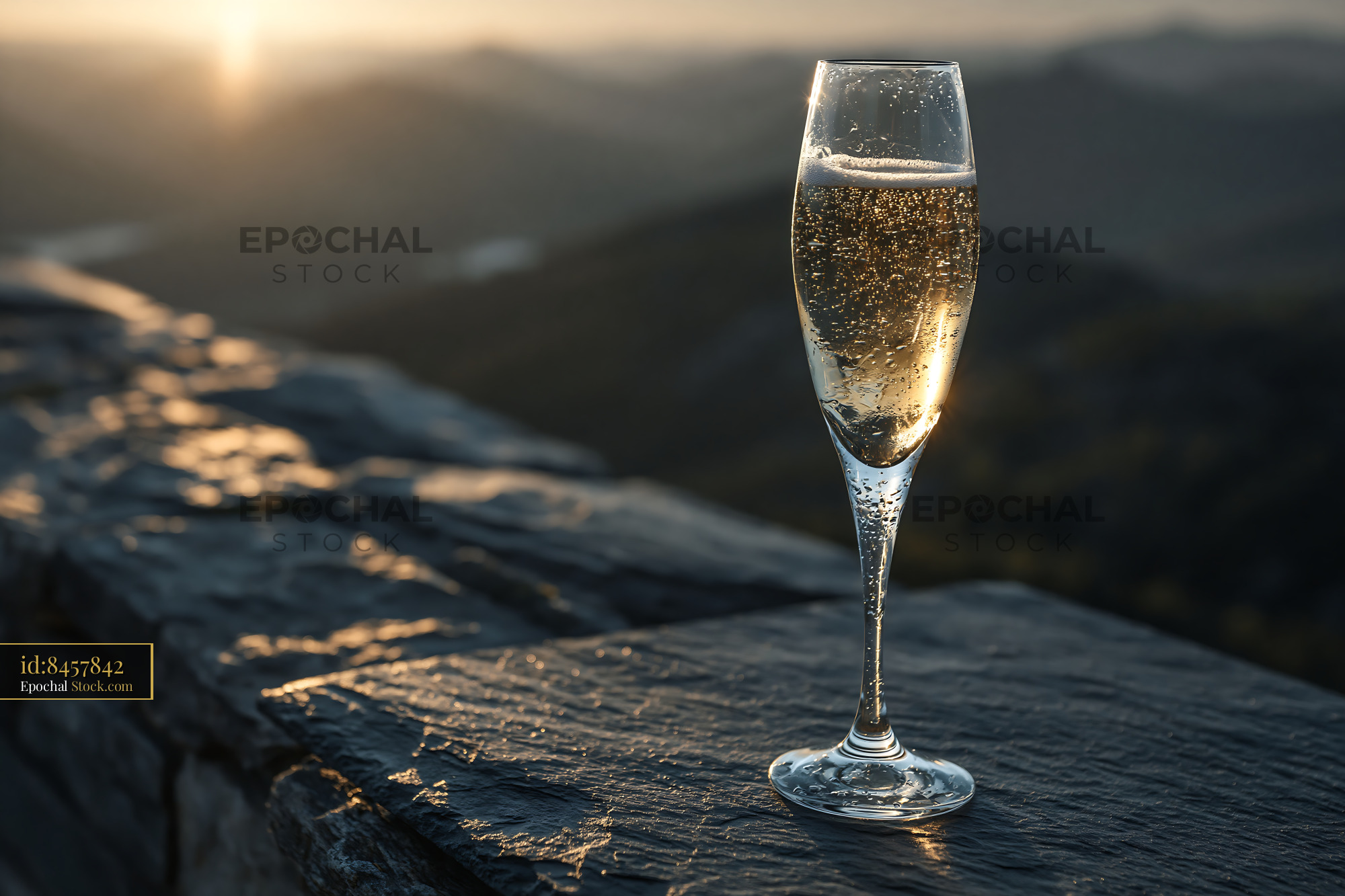Glass of sparkling wine on a stone terrace at sunset with mountain vie - stock photo