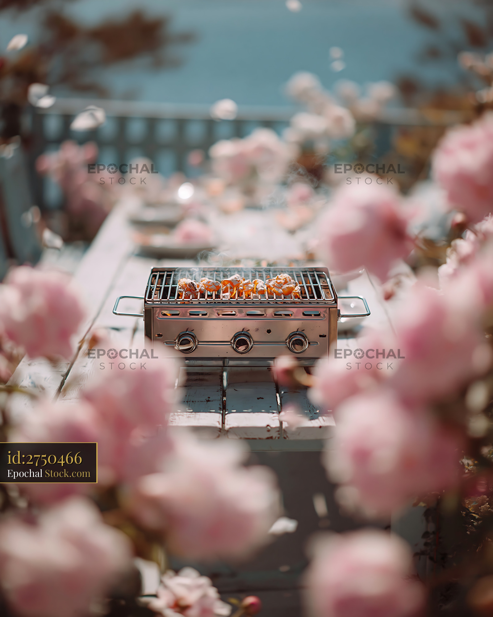 Small gas grill on a white wooden table surrounded by pink roses - stock photo