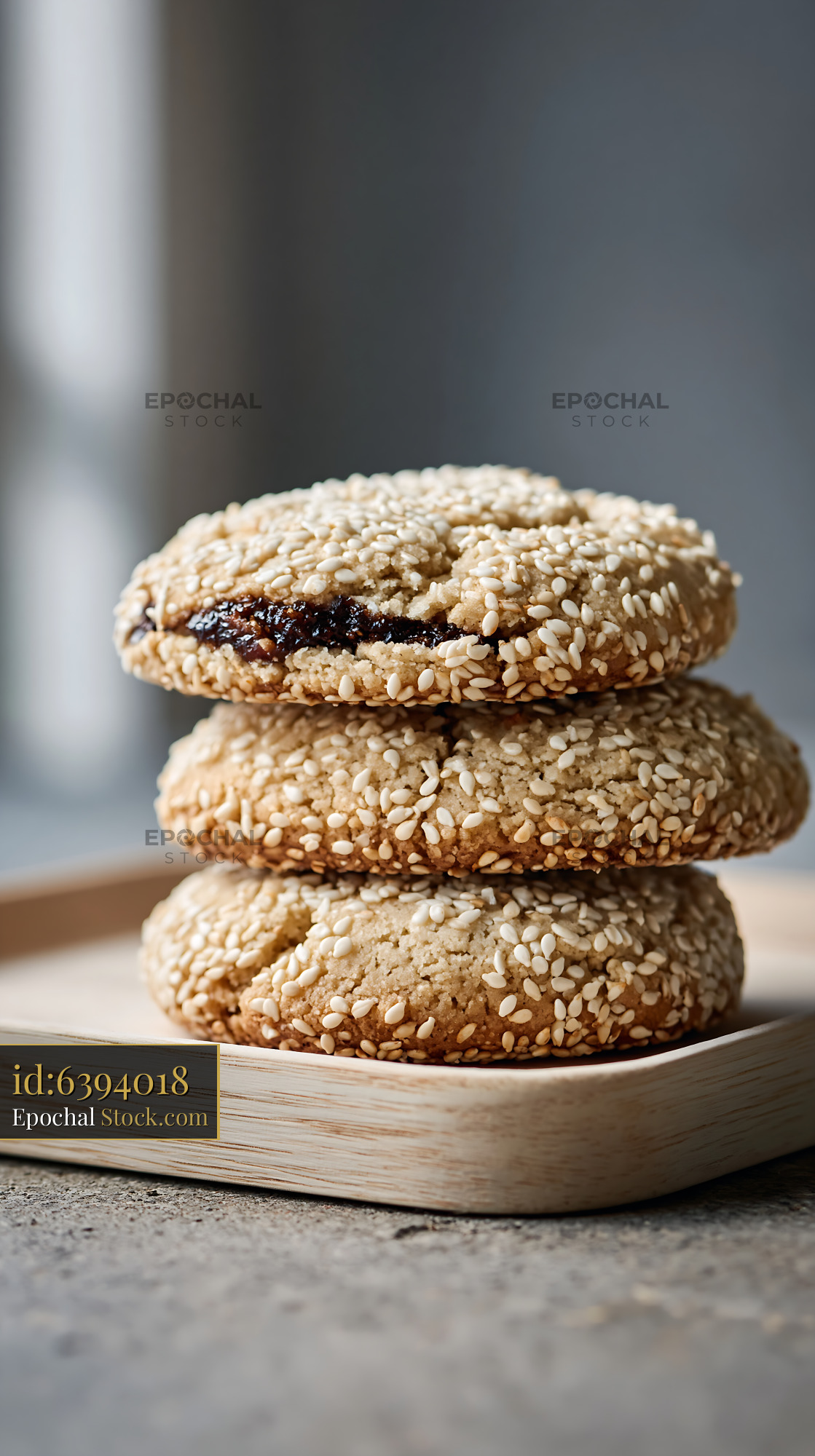 Tahini date biscuits with sesame seeds stacked on a wooden tray - stock photo