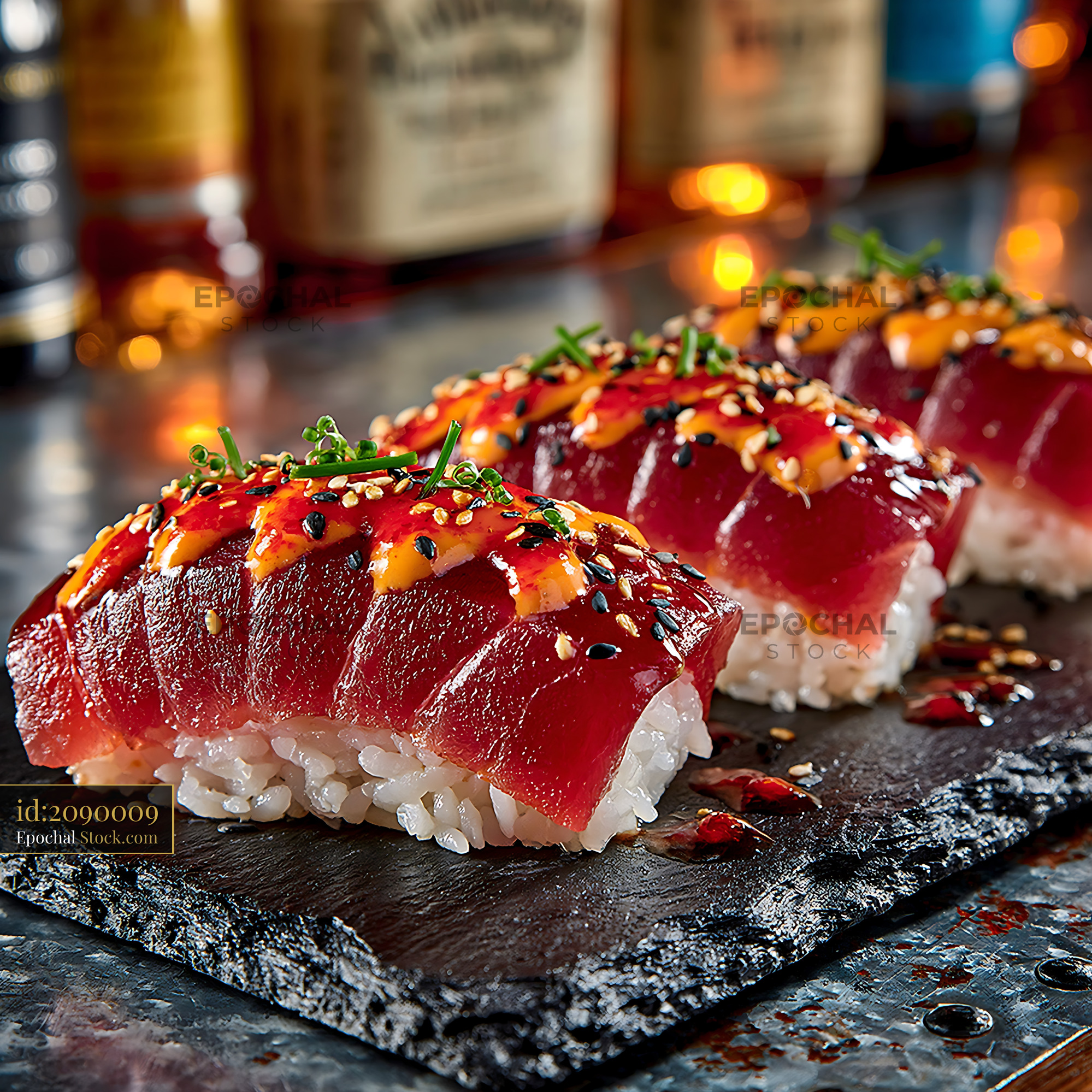 Tuna nigiri sushi topped with sriracha mayo and sesame on slate - stock photo