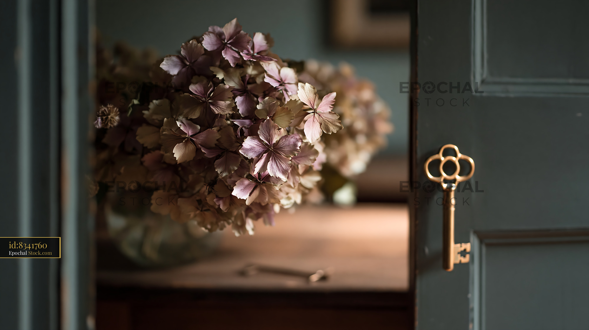 Dry hydrangea bouquet on table behind a door with a vintage key - stock photo