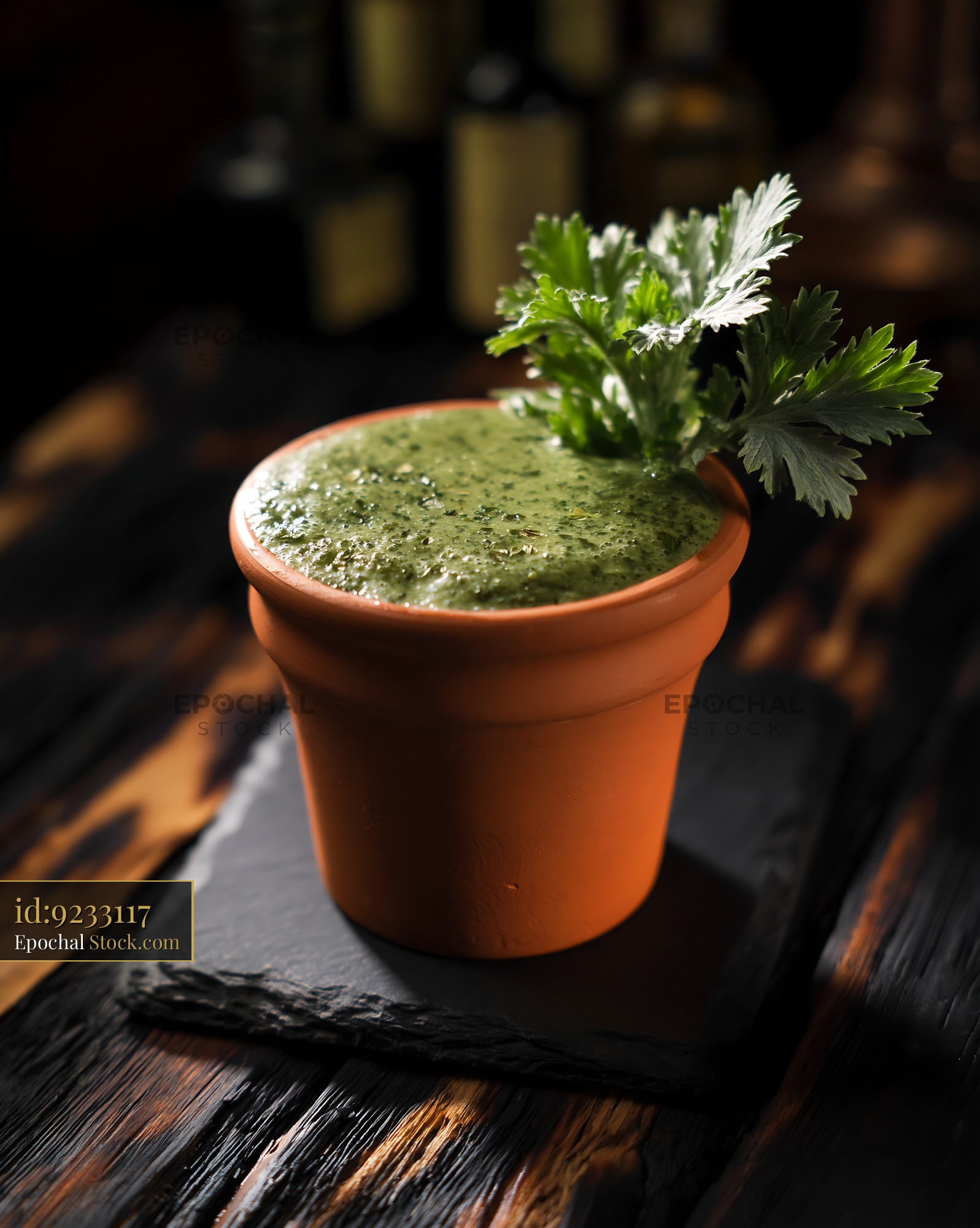 Green mugwort herb smoothie in a clay pot on a dark wooden surface - stock photo
