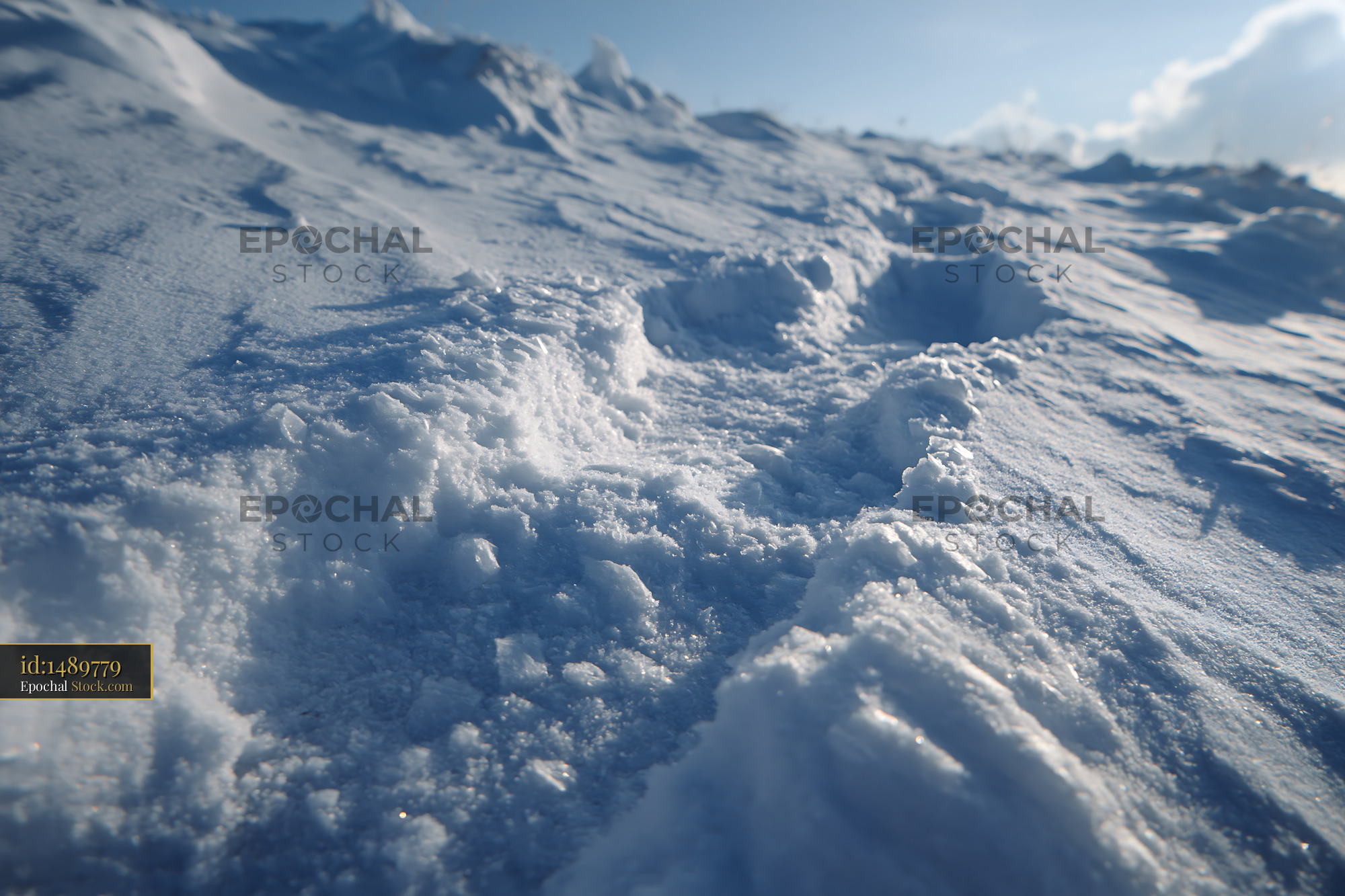 Footprints in deep snow on a mountain during a sunny winter day - stock photo