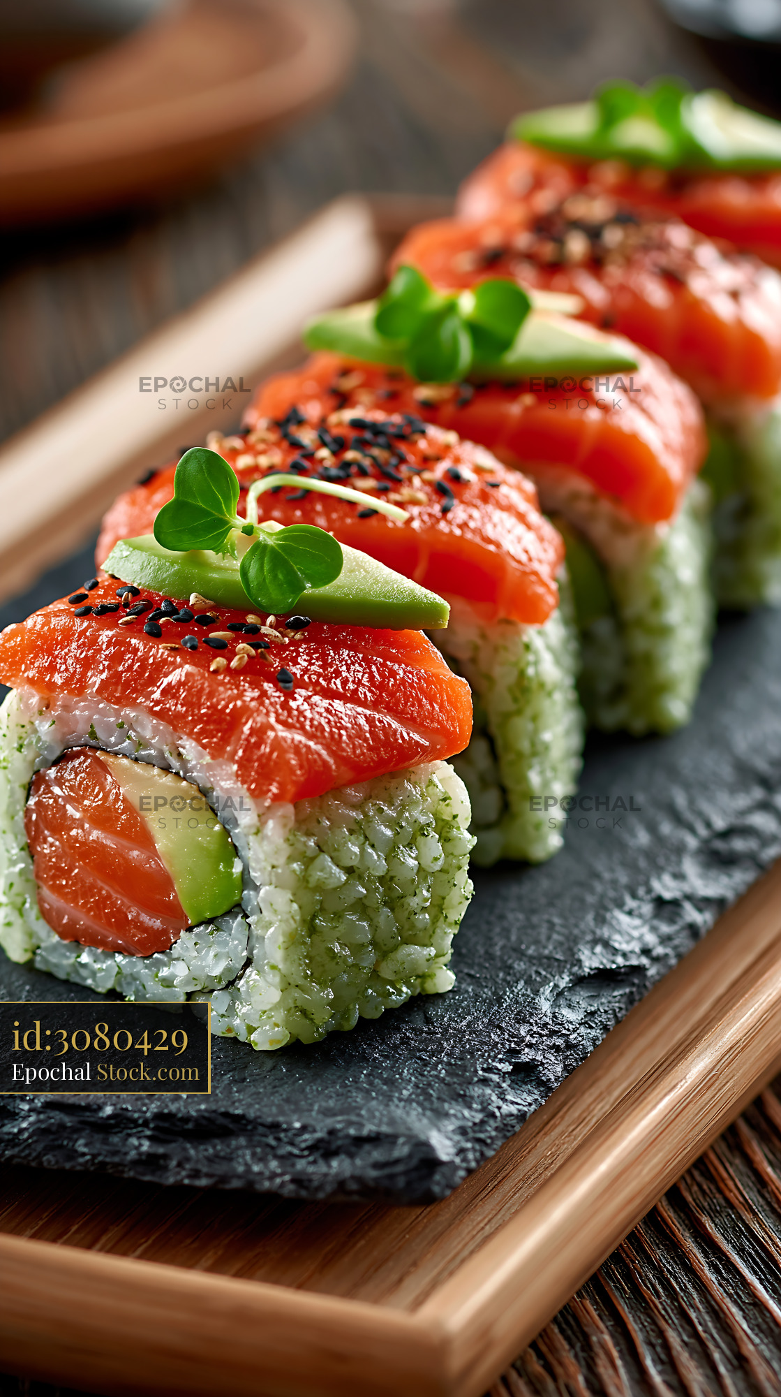 Salmon uramaki with matcha infused rice and avocado on slate board - stock photo
