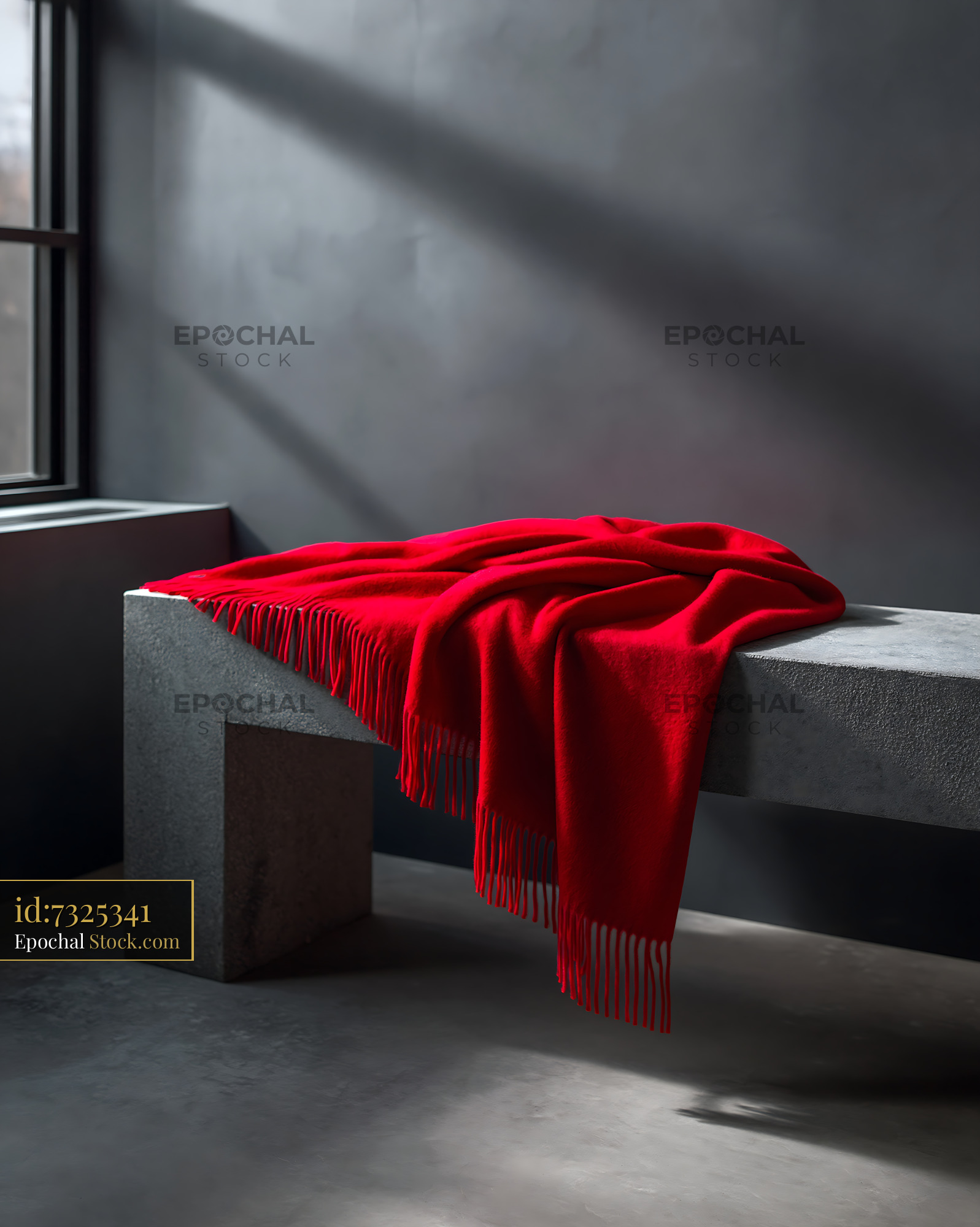 Red wool throw on concrete bench in a moody minimalist room - stock photo
