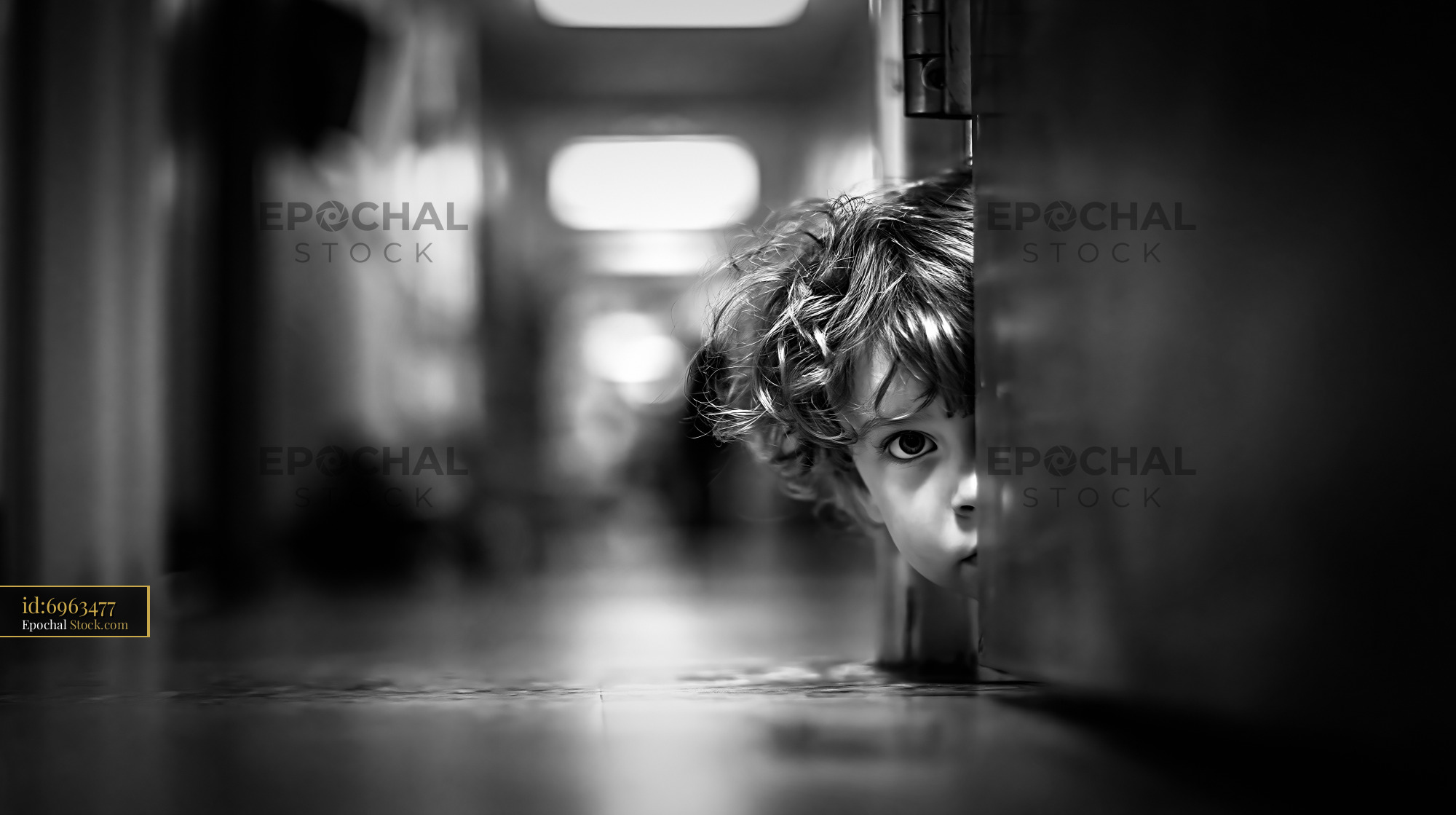 Young child with curly hair peeking from behind a classroom door - stock photo