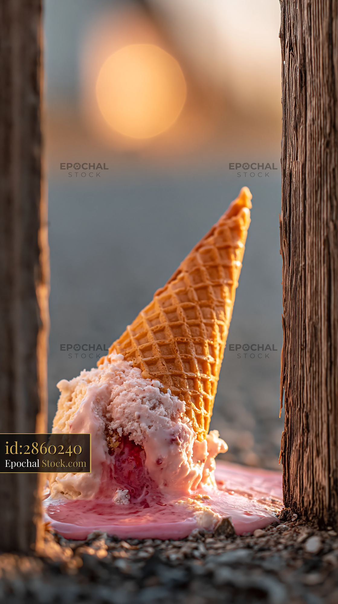 Abandoned ice cream cone melting on the ground at sunset - stock photo