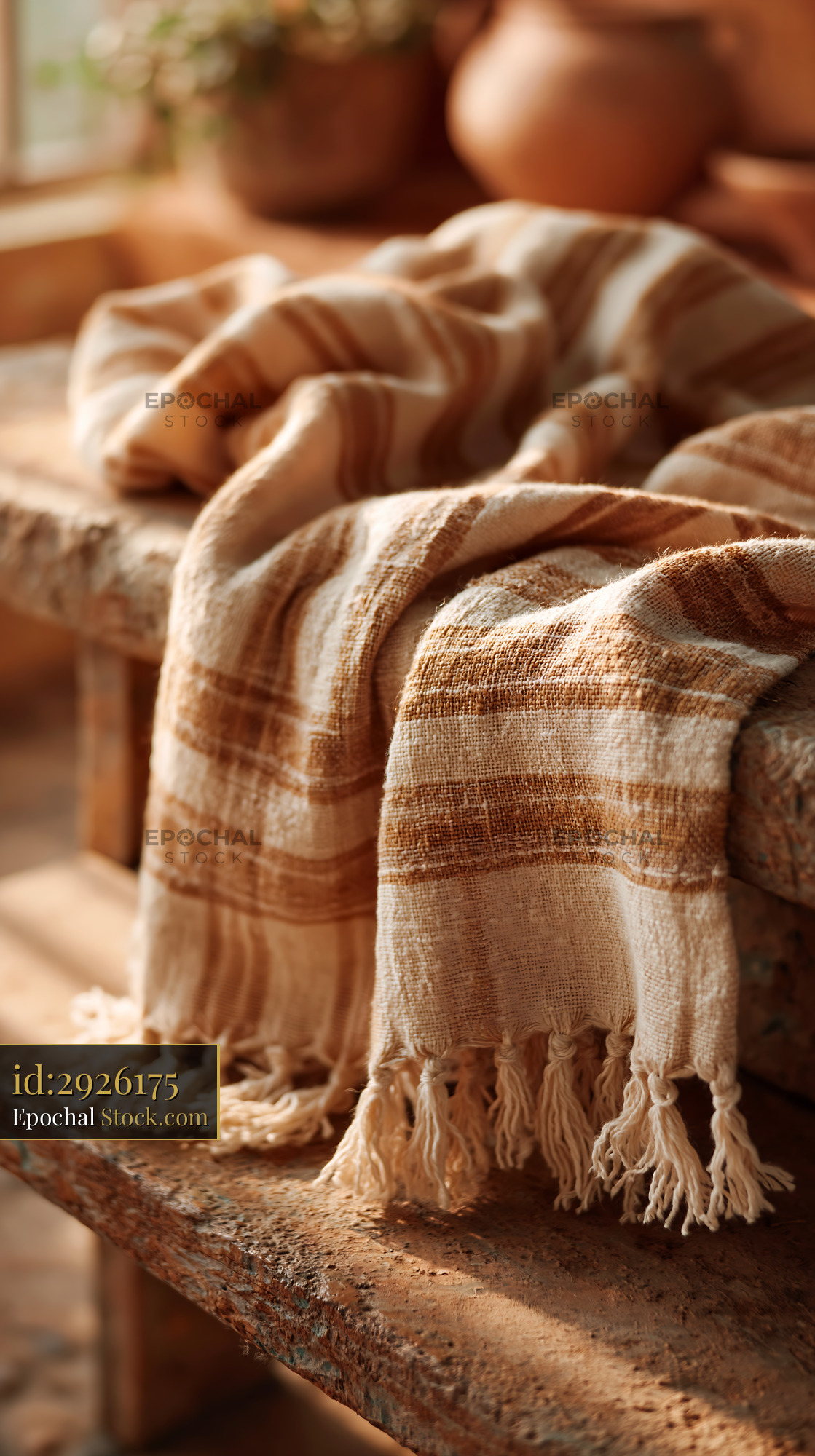 Woven striped throw on bench in sunlit rustic interior - stock photo