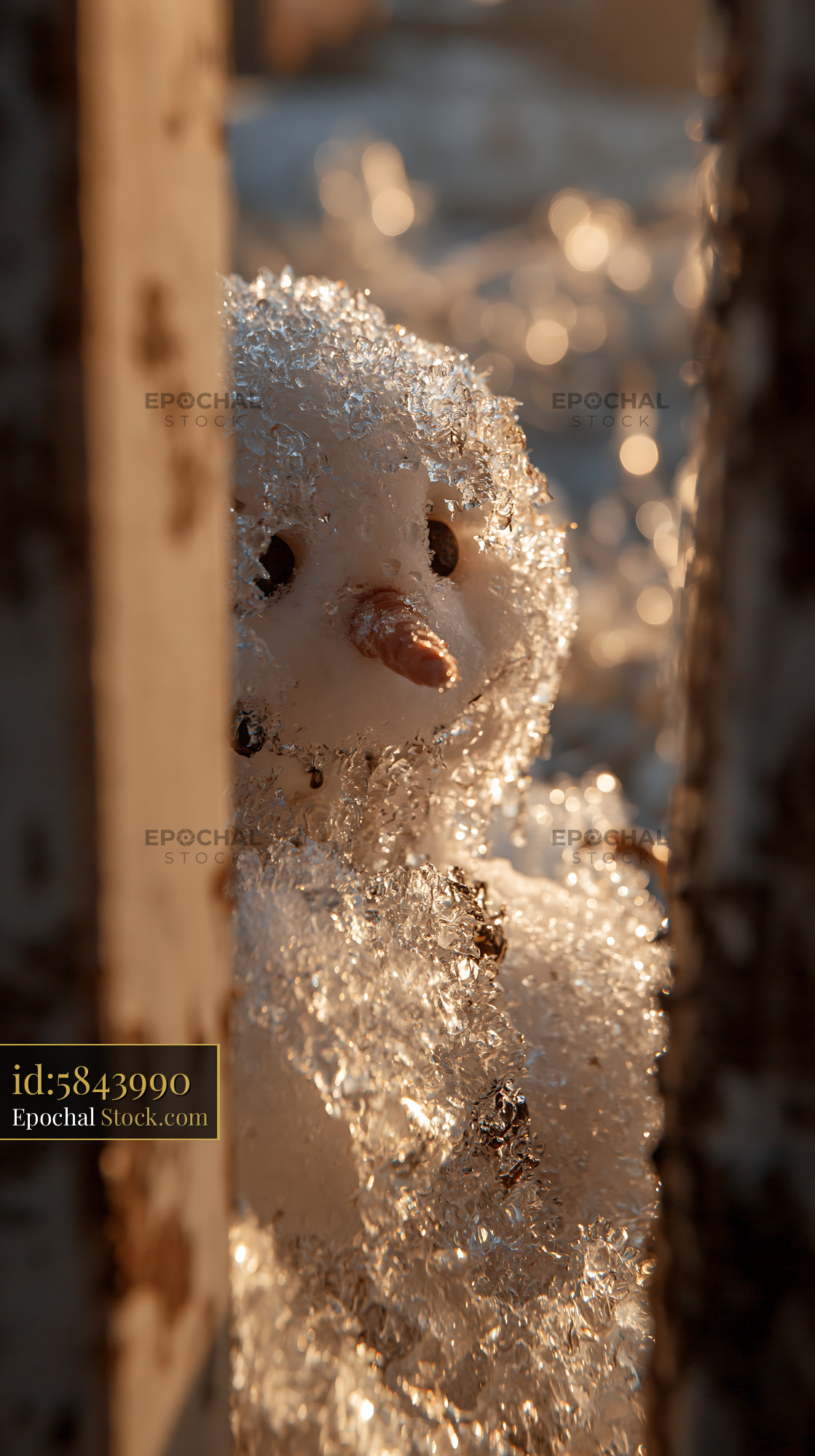 Small snowman melting in golden spring sunlight behind a wooden fence - stock photo