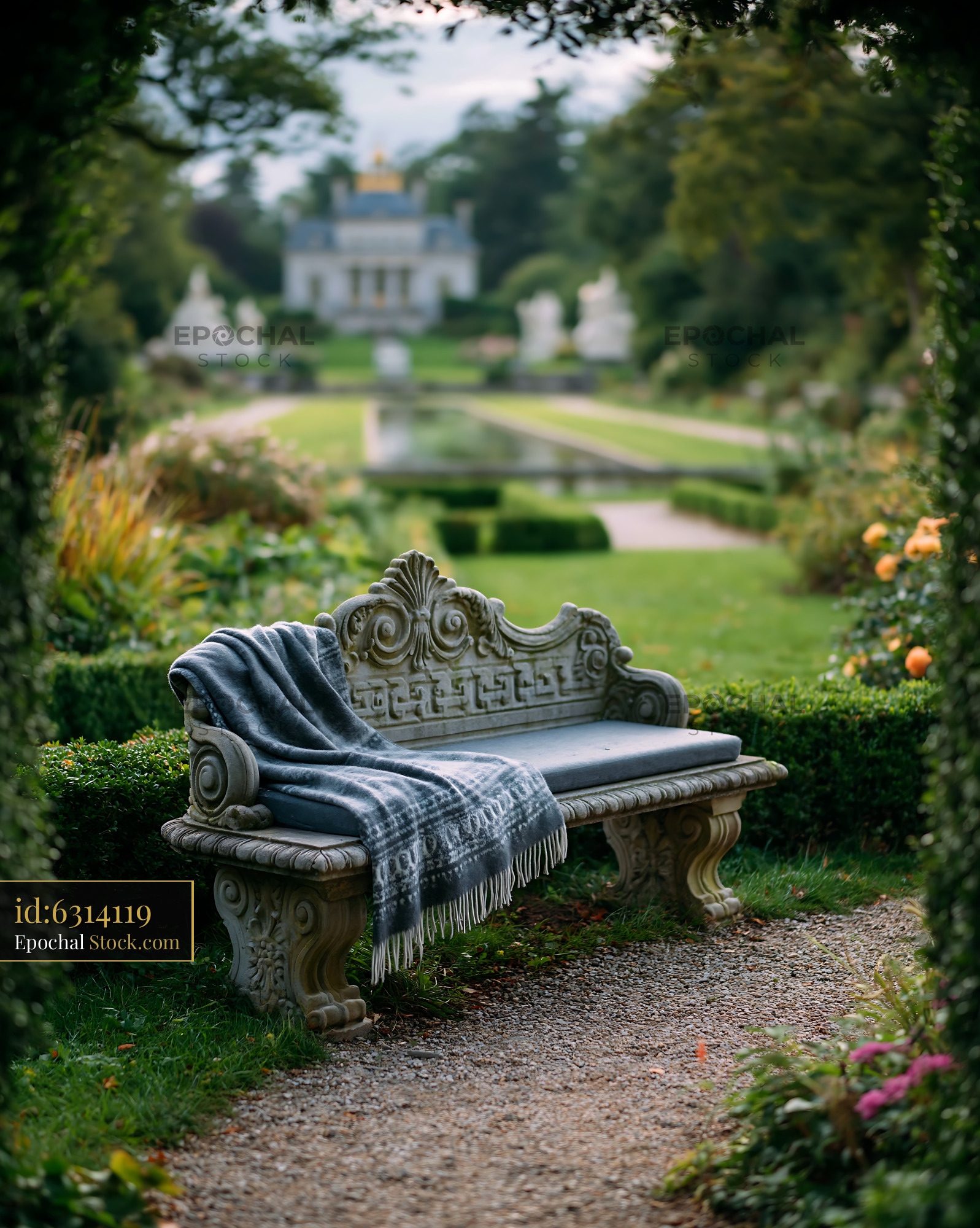 Striped throw on ornate stone bench in a formal garden - stock photo