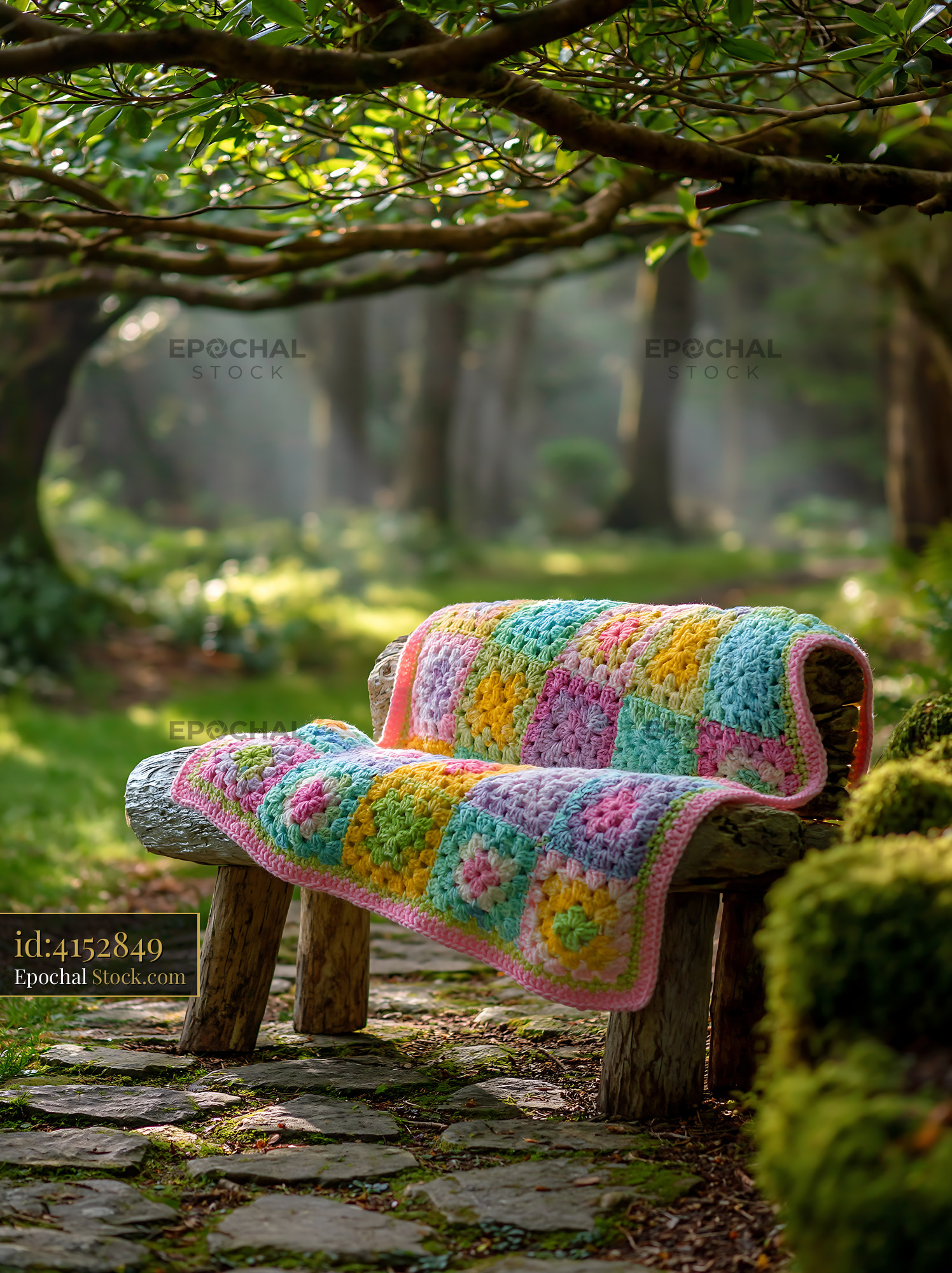 Colorful crochet blanket on rustic log bench in sunlit forest - stock photo