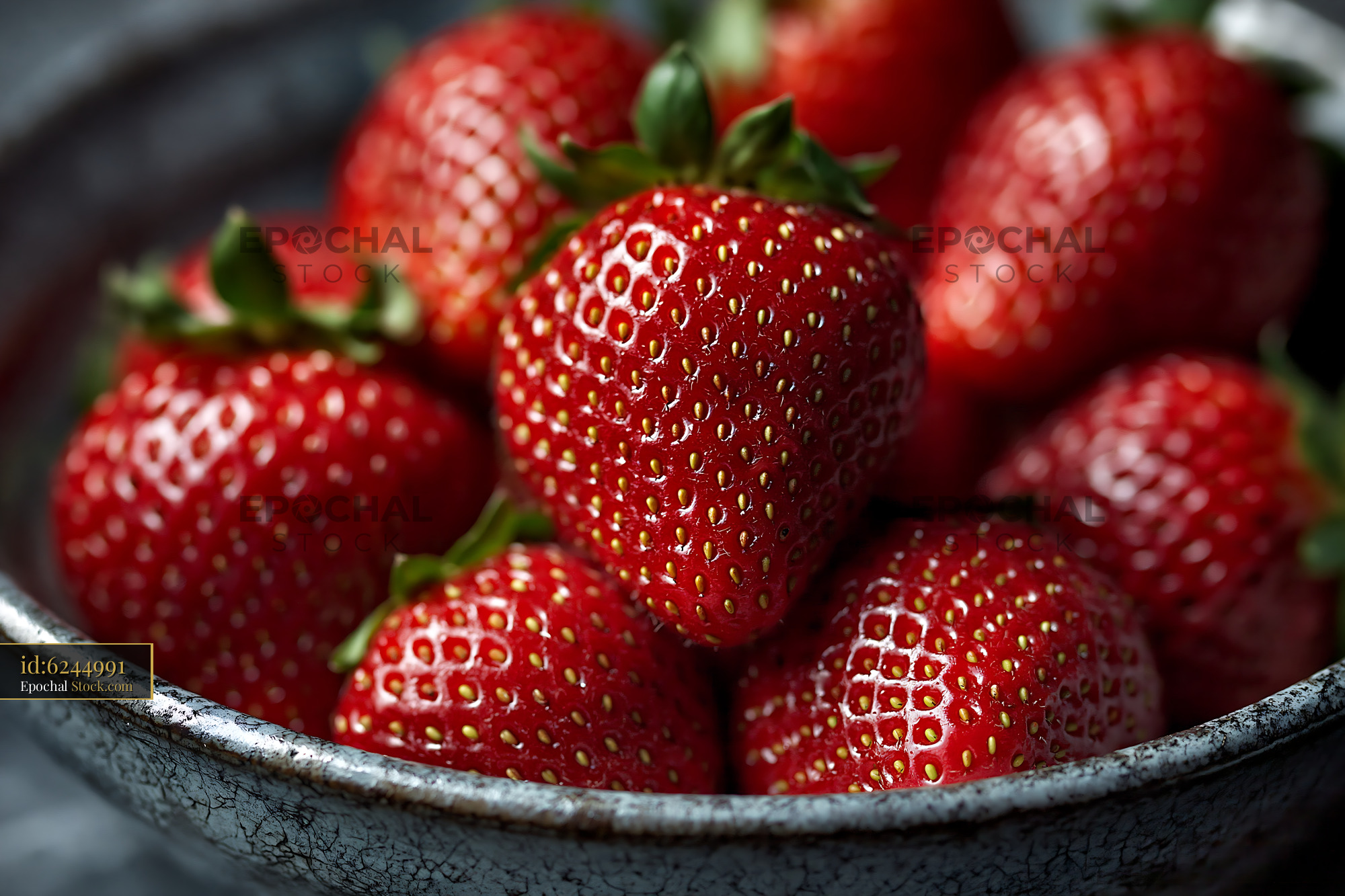 Fresh strawberries in a rustic ceramic bowl with dramatic lighting - stock photo