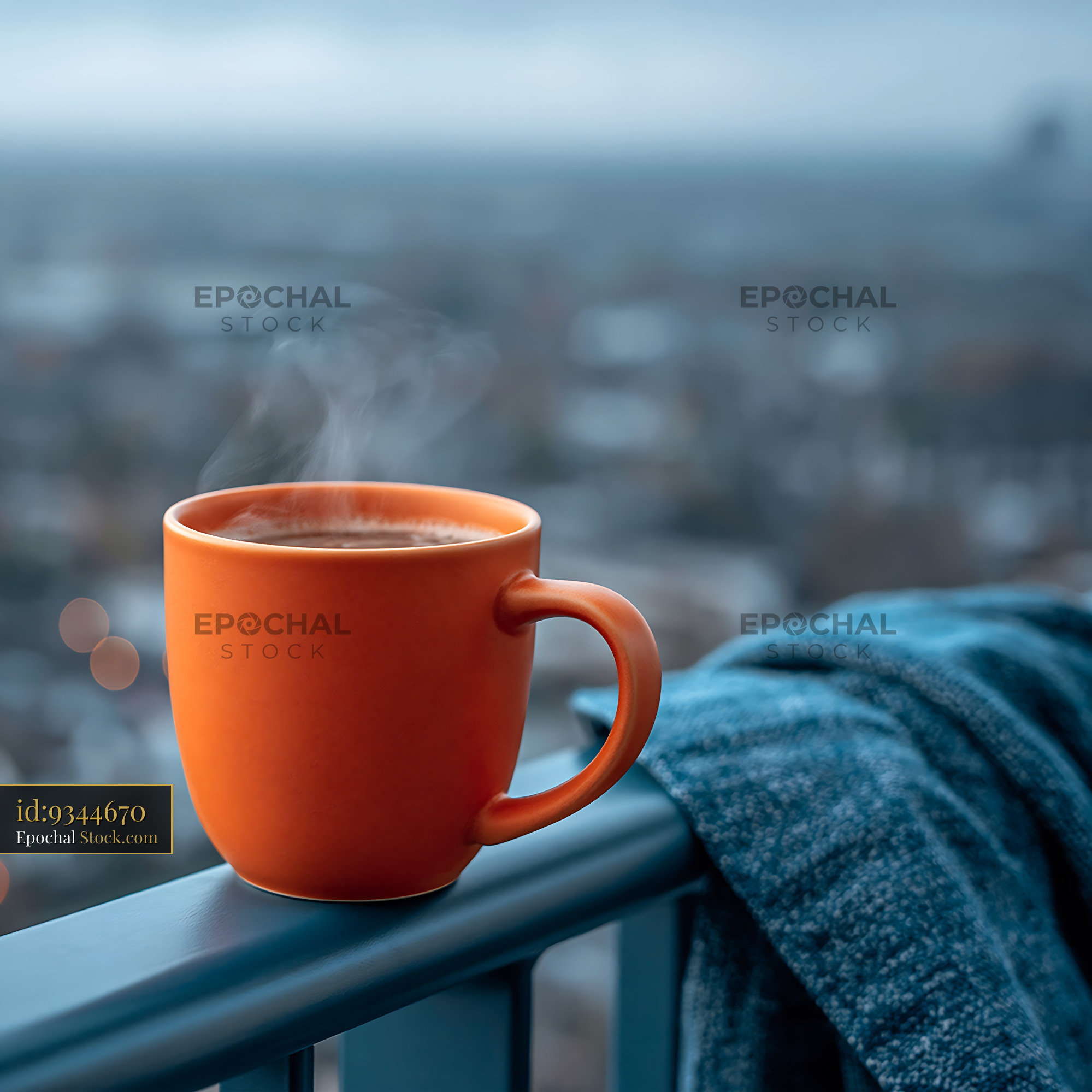 Orange coffee cup with steam on a balcony overlooking the city - stock photo