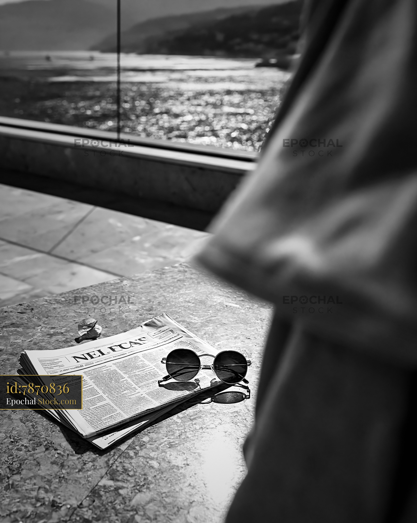 Sunglasses and newspaper on a stone table with a luxury hotel balcony  - stock photo