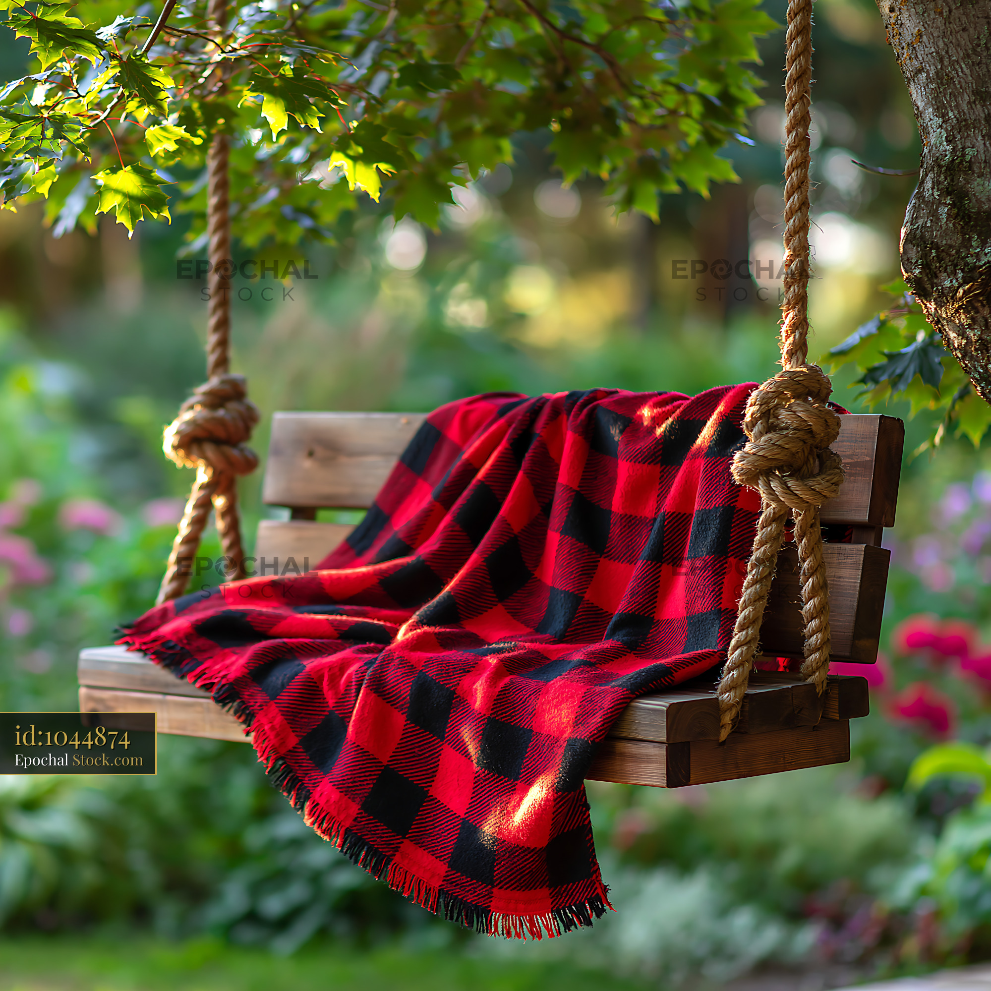Rustic wooden garden swing with red plaid throw blanket in sunlight - stock photo