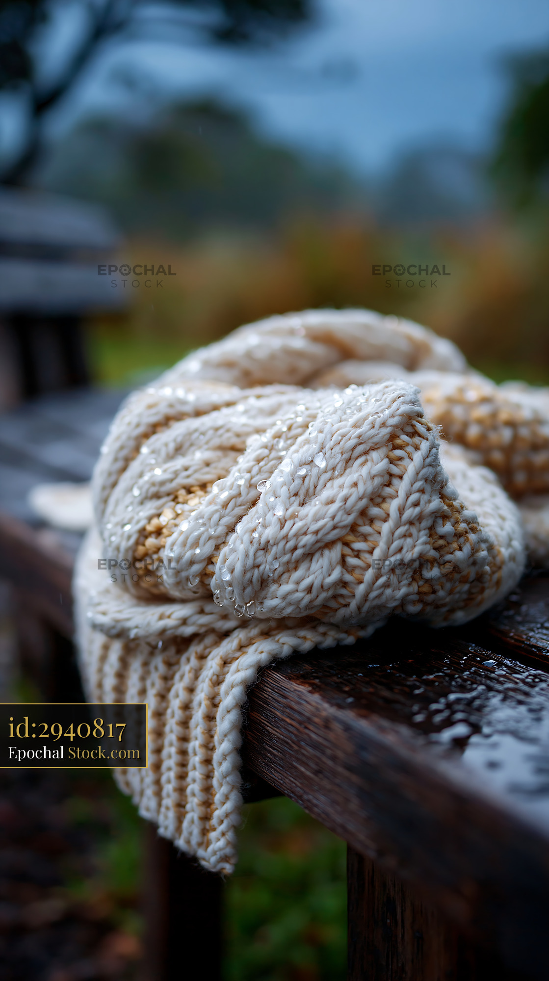 Cozy patterned blanket left on a wet wooden park seat in the rain - stock photo