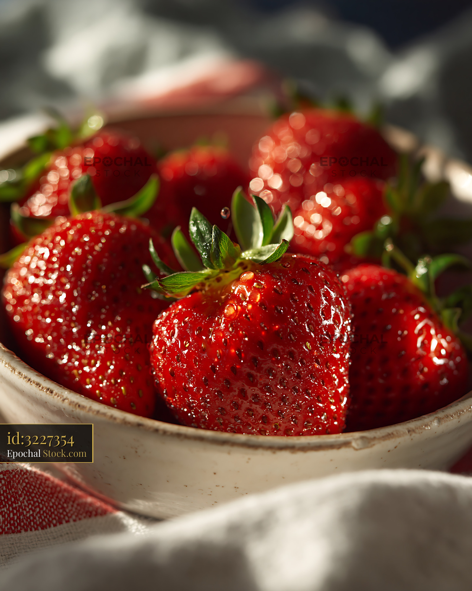 Fresh strawberries ceramic bowl with water droplets in warm sunlight - stock photo