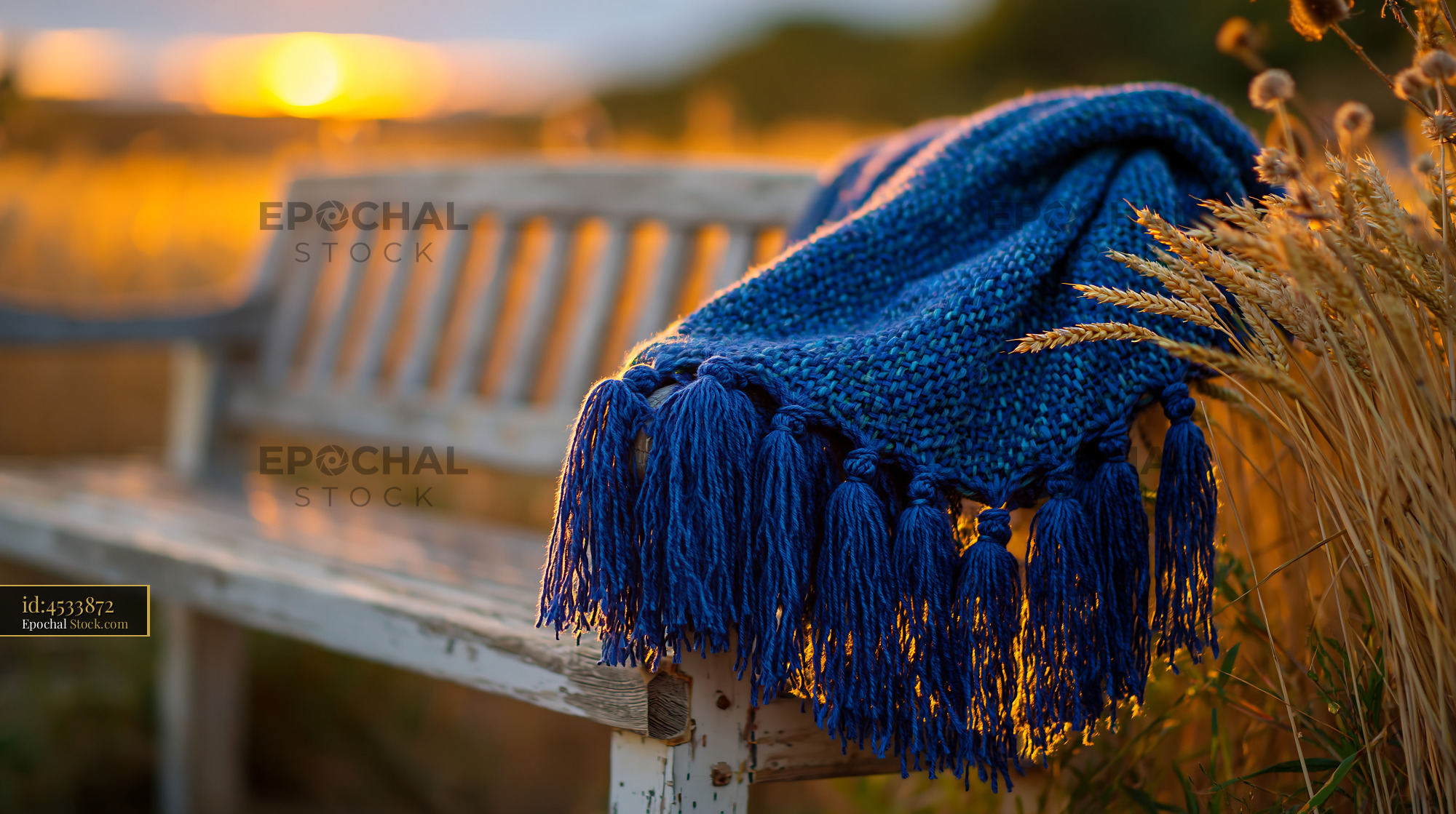 Blue knitted blanket on a white wooden bench at sunset - stock photo