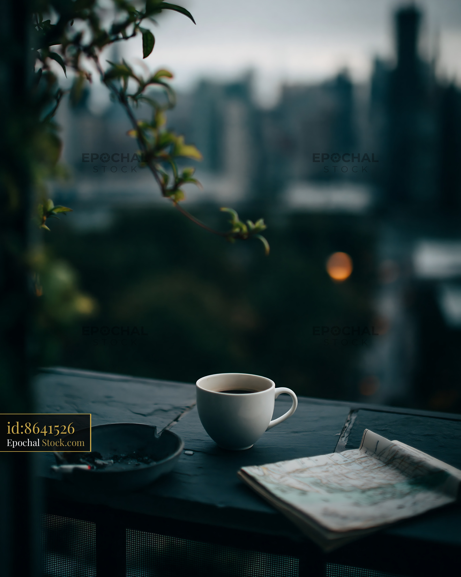 Coffee cup on a balcony overlooking a blurred city skyline at dusk - stock photo