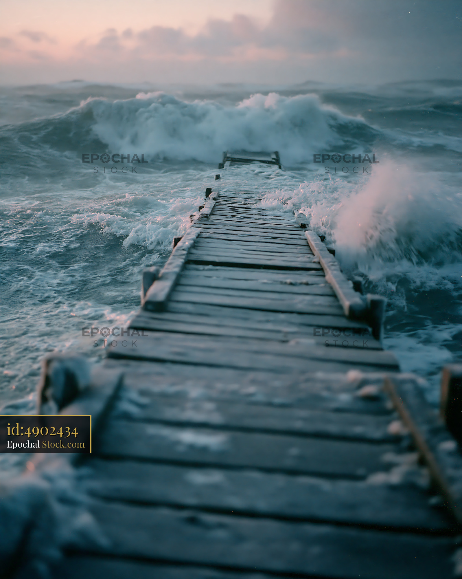 Old wooden pier facing powerful crashing waves during winter dusk - stock photo