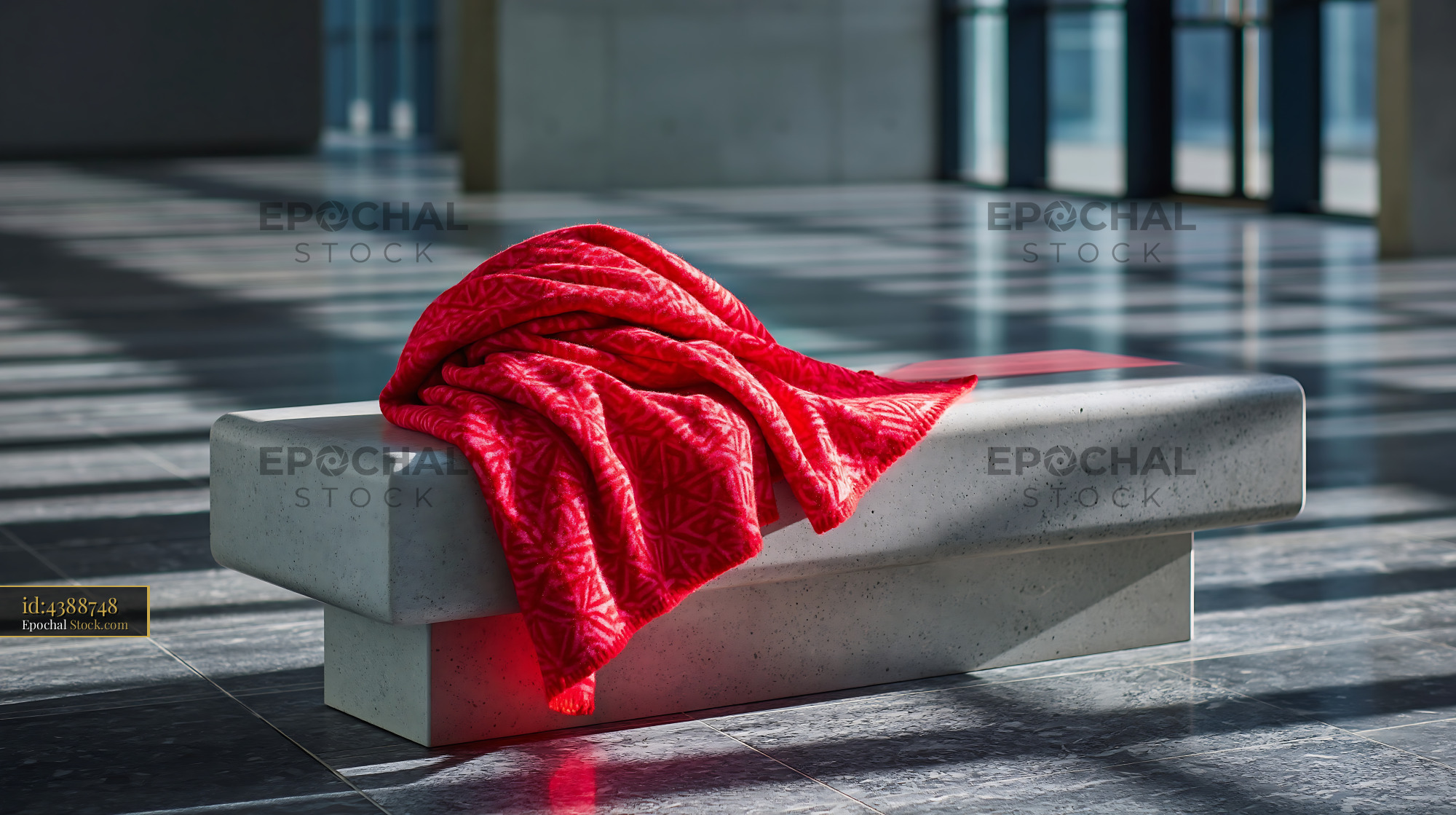 Red patterned throw on a minimalist concrete bench in a sunlit hall - stock photo
