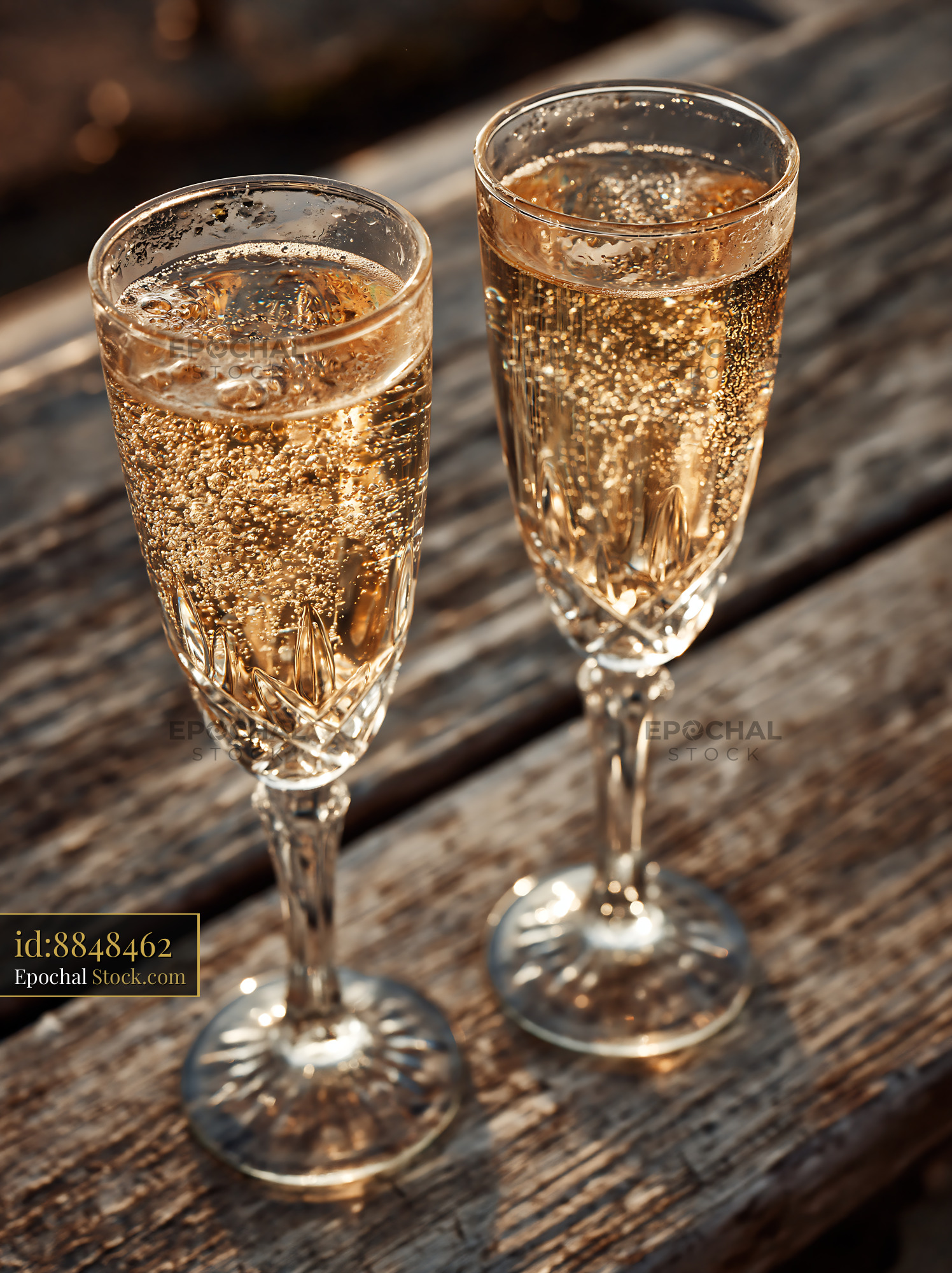 Two crystal glasses of sparkling wine on a rustic wooden terrace at su - stock photo