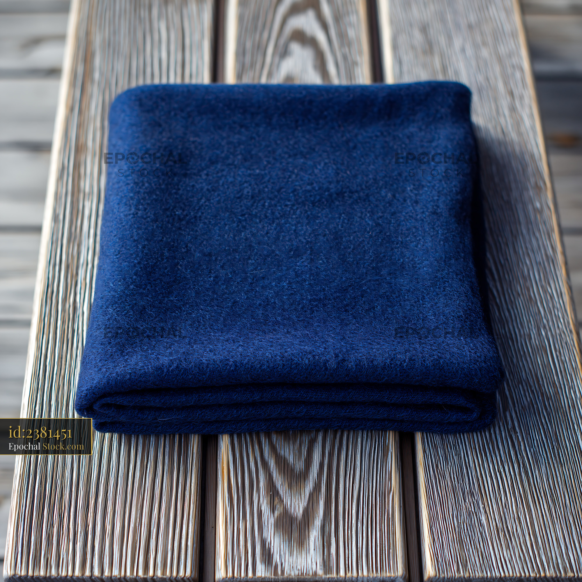 Dark blue wool blanket folded on a weathered wooden garden bench - stock photo