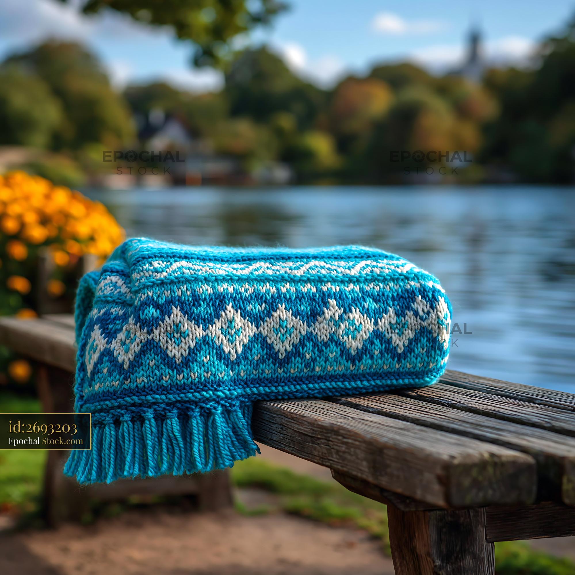 Blue patterned blanket on a wooden park seat by a peaceful lake - stock photo