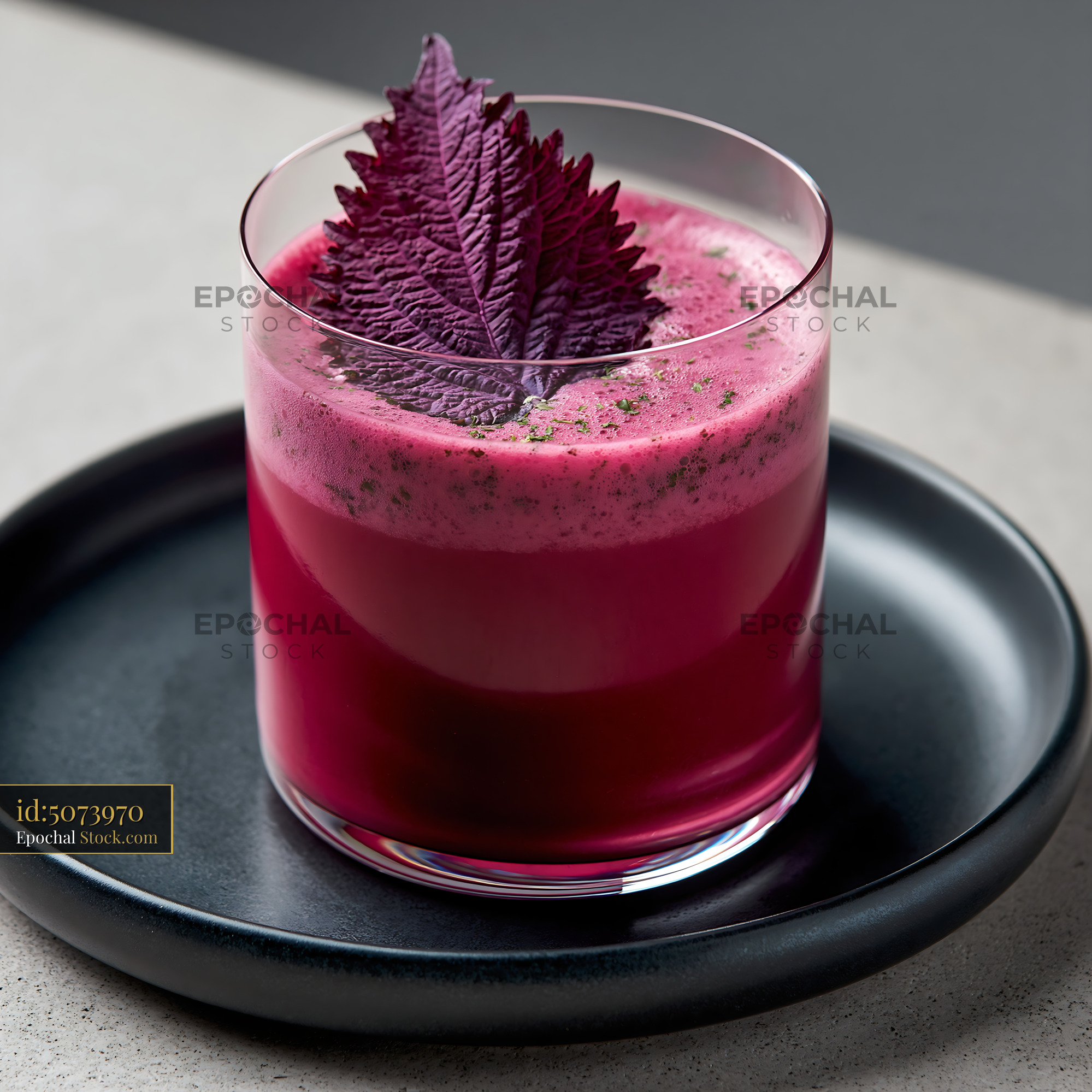 Refreshing pink shiso leaf smoothie with purple garnish on black plate - stock photo
